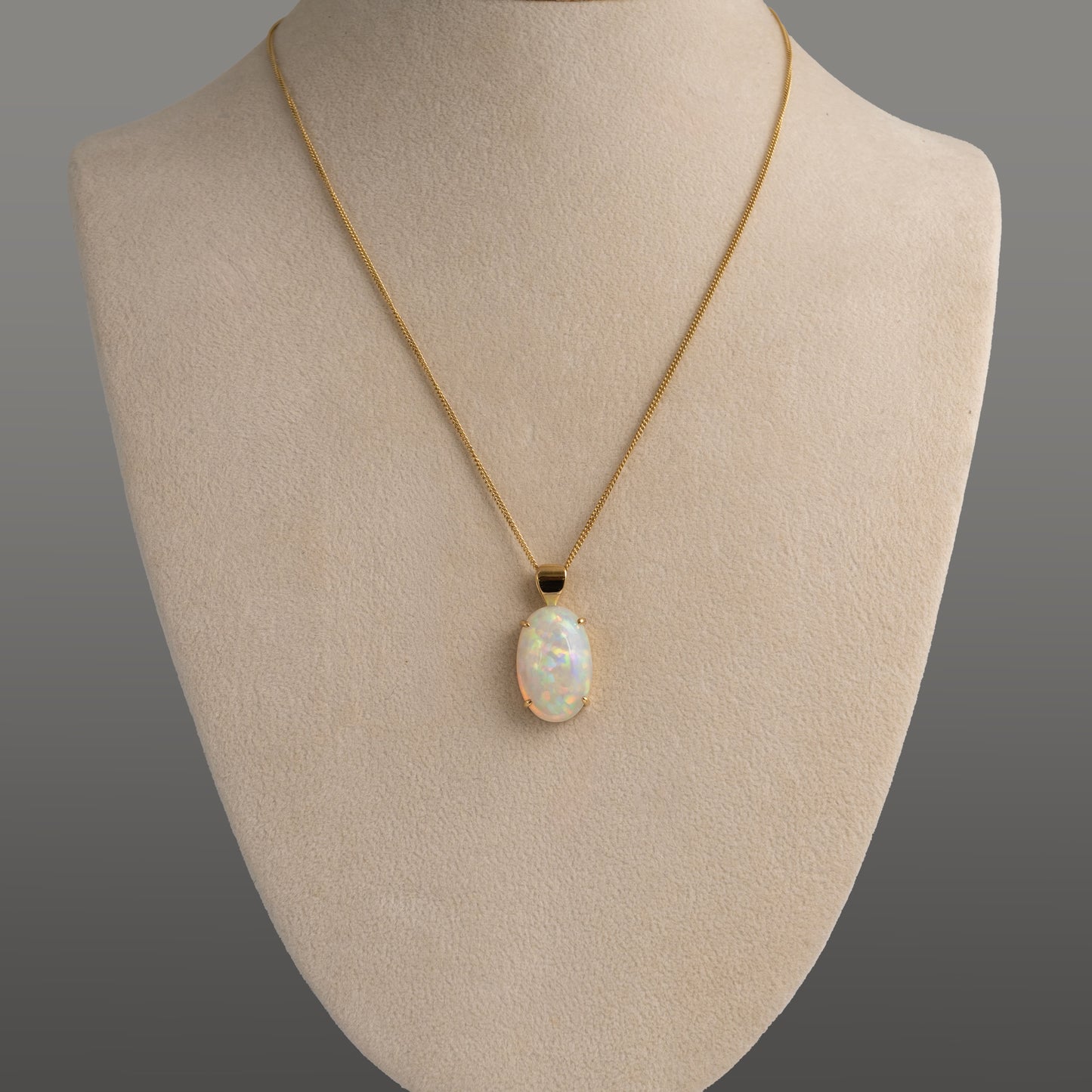 Necklace with an opal pendant on a mannequin bust against a gray background