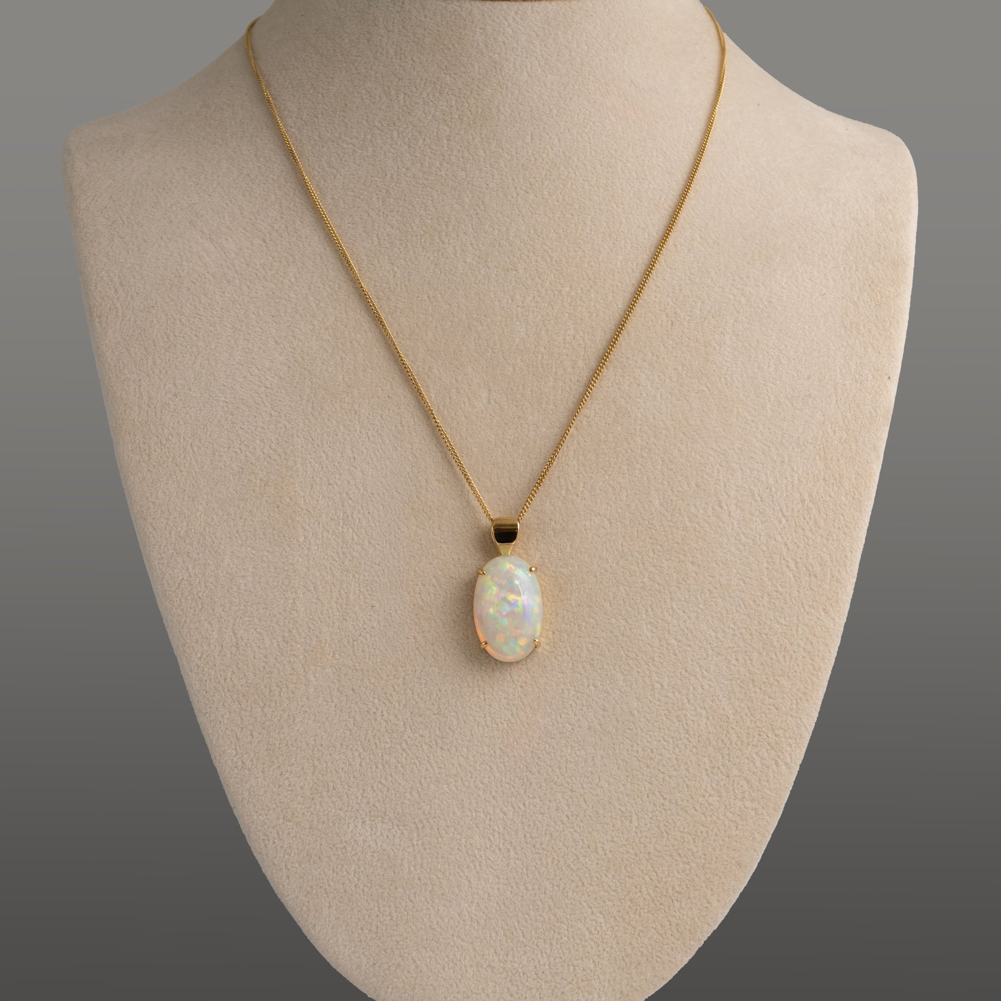 Necklace with an opal pendant on a mannequin bust against a gray background