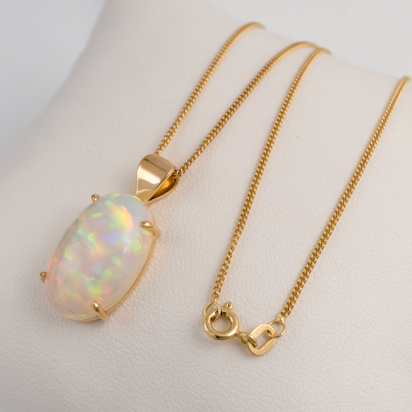Gold necklace with an opal pendant on a white background