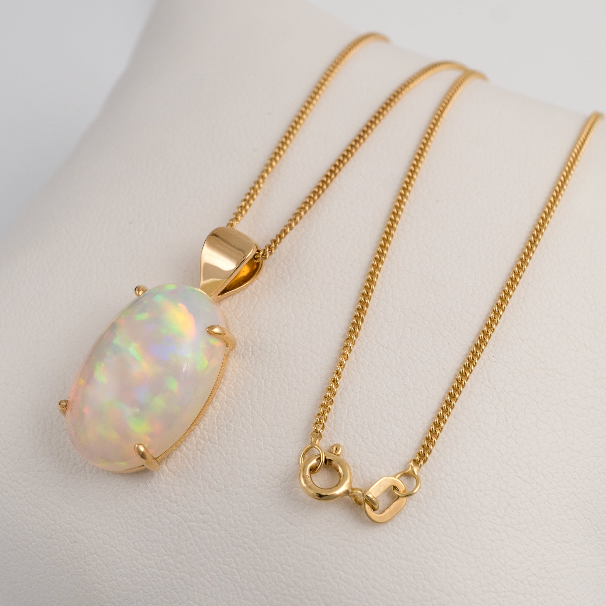 Gold necklace with an opal pendant on a white background