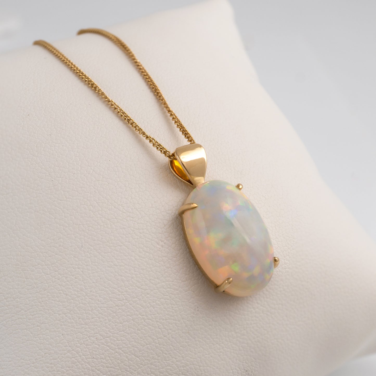 Opal stone pendant necklace on a mannequin bust with a plain background