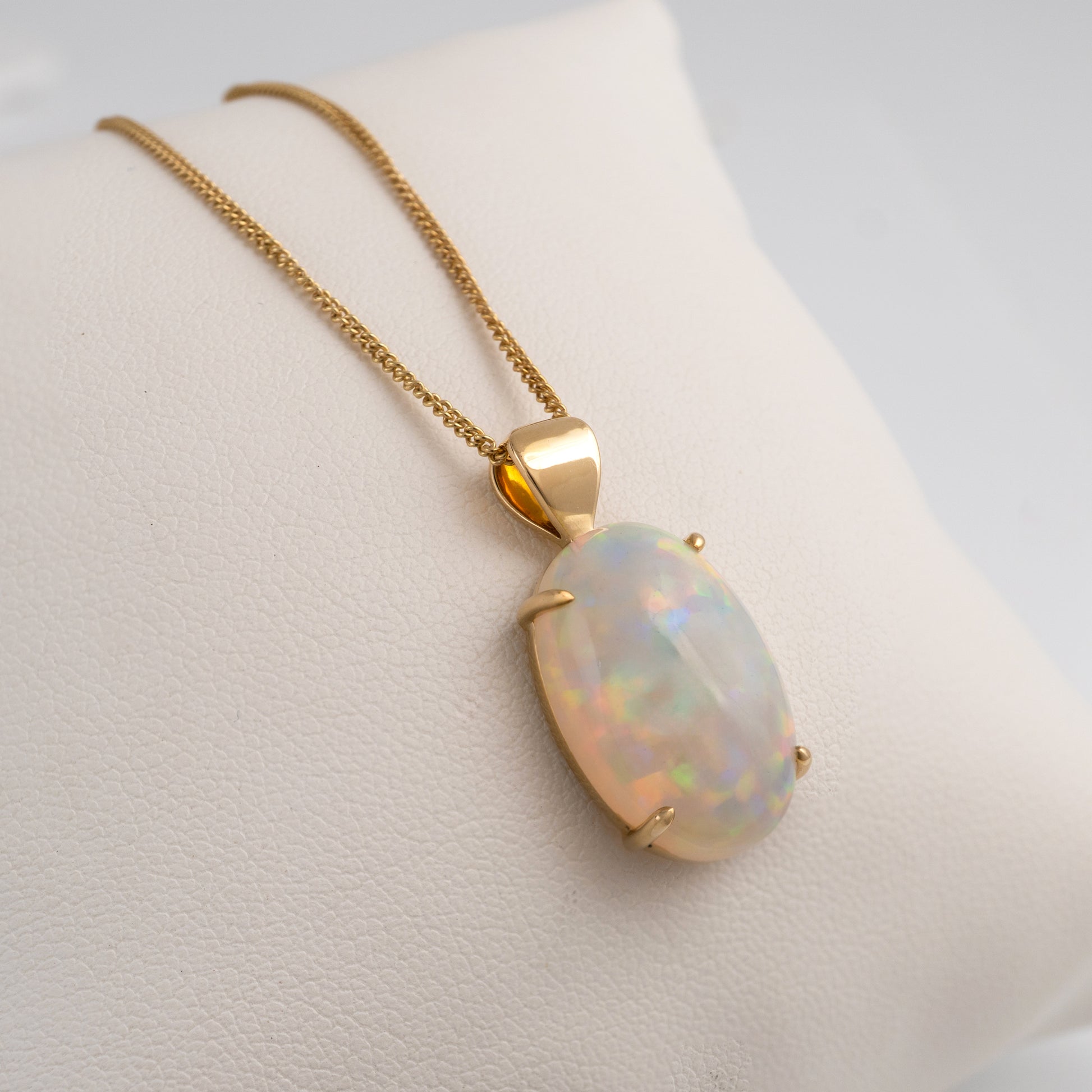 Opal stone pendant necklace on a mannequin bust with a plain background