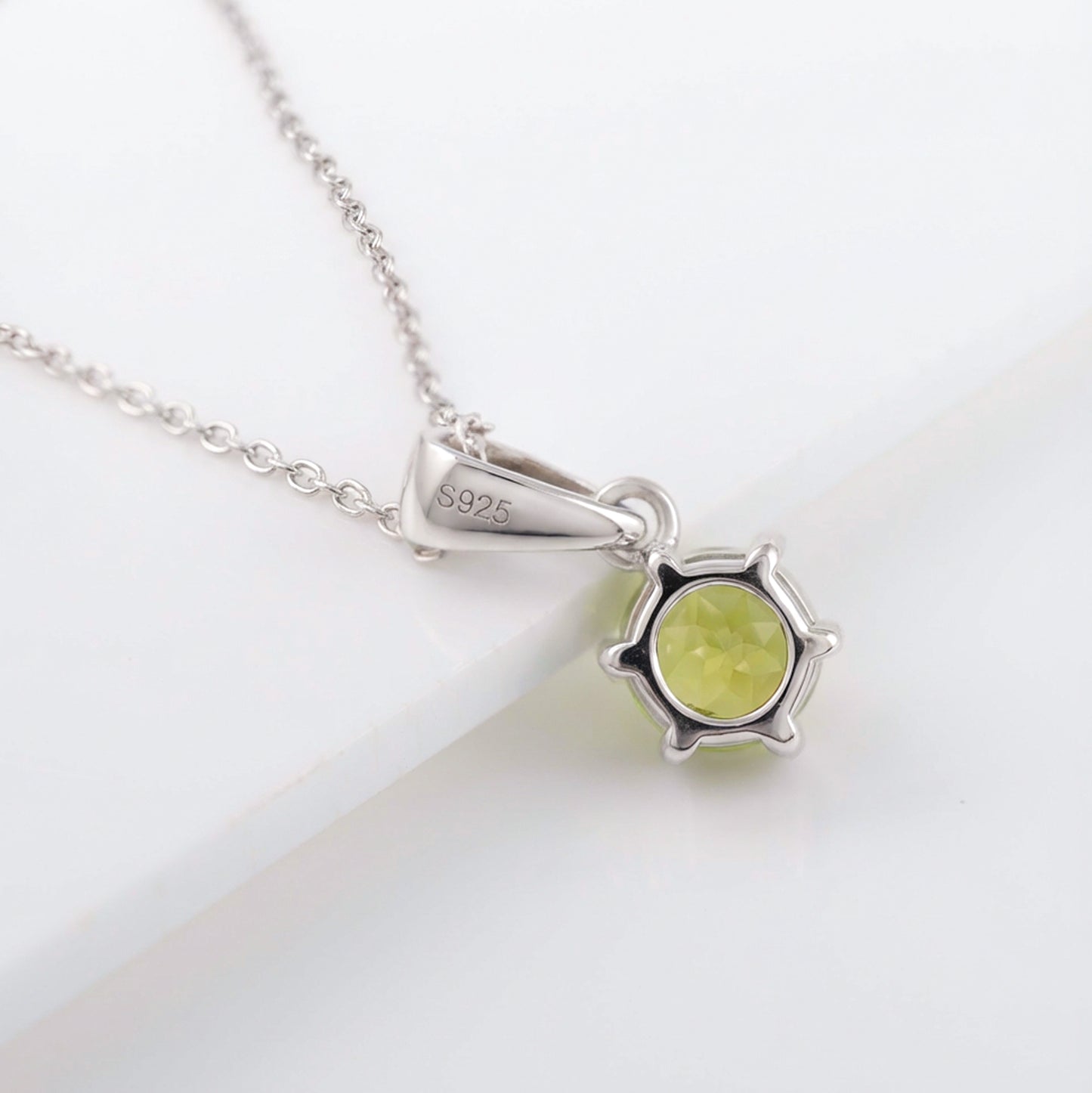 Silver necklace with a green pendant on a white background