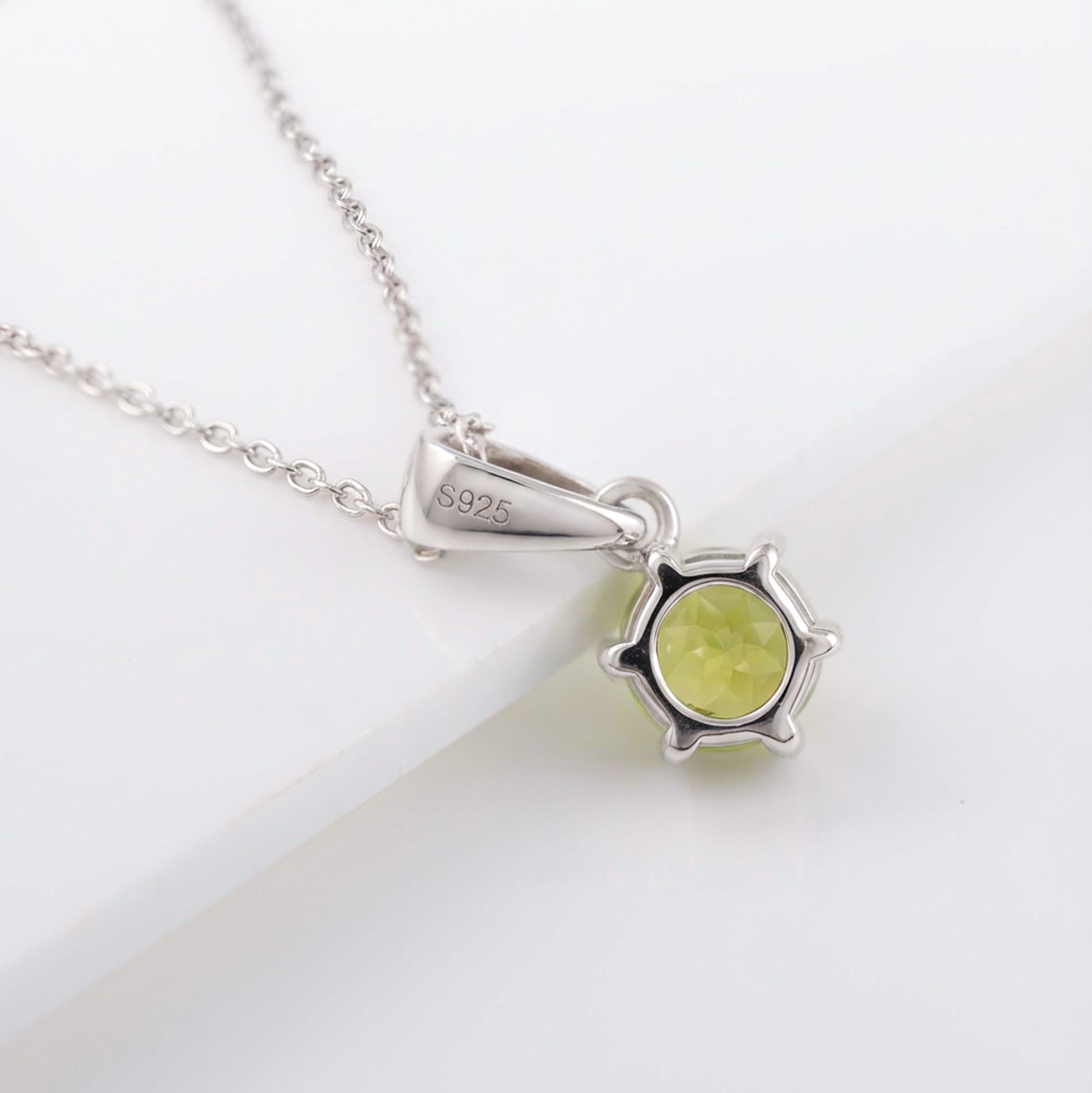 Silver necklace with a green pendant on a white background