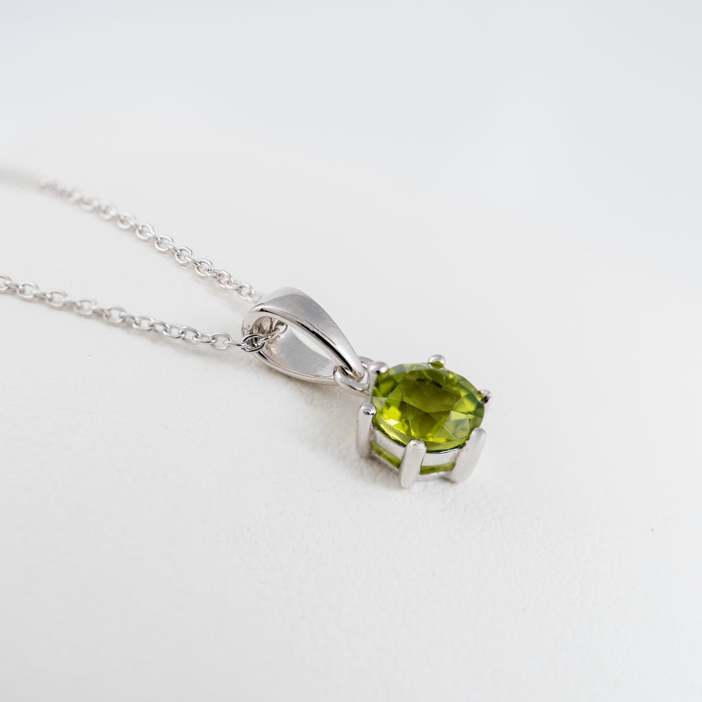 Silver necklace with a natural peridot pendant on a white background
