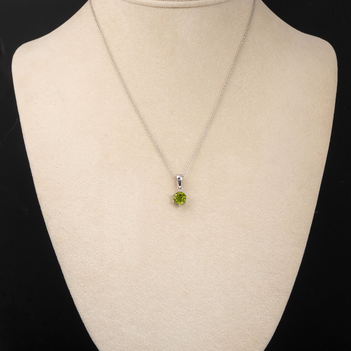Necklace with a peridot gemstone on a mannequin bust against a black background
