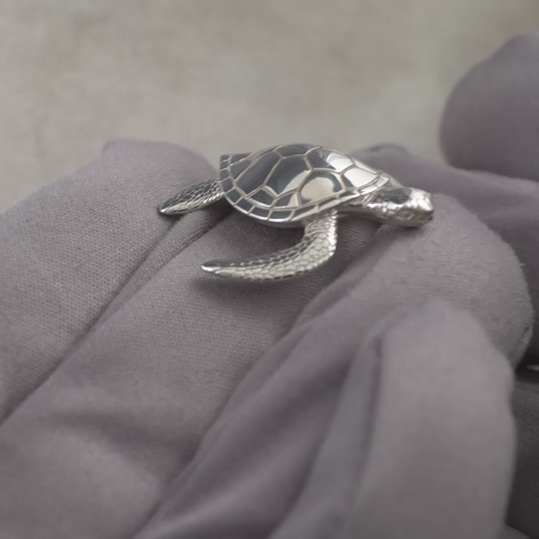 sterling silver sea turtle minature gift being held in a hand with grey gloves 