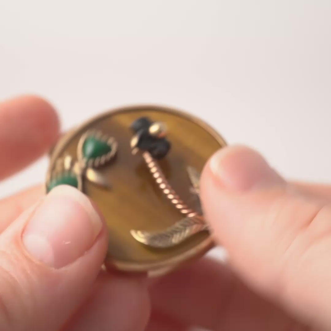 Video showcasing a vintage 9ct gold butterfly pendant with tiger's eye gemstone background, malachite wings, black onyx flower, and rose gold stem. Features include side views, reverse side, clean hallmarks, and intricate craftsmanship from all angles.