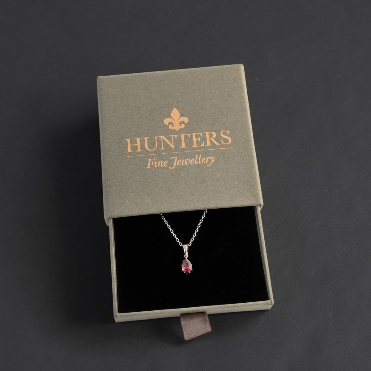 Rhodolite garnet teardrop necklace displayed in a Hunters Fine Jewellery presentation box with a black interior.