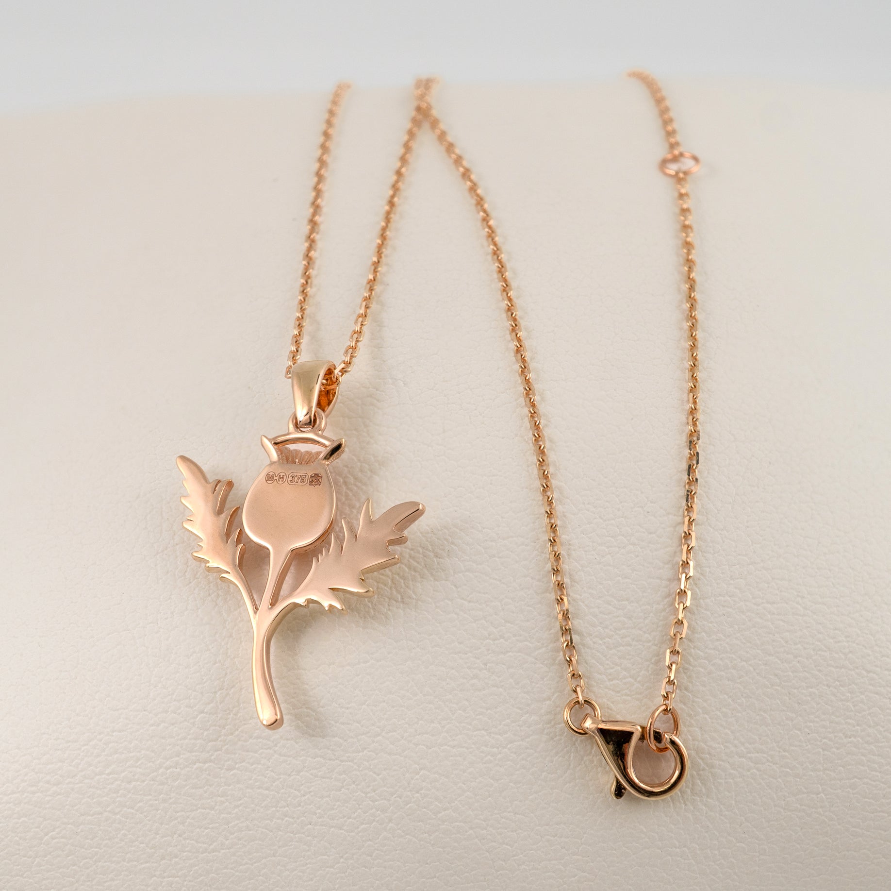 Rose gold thistle pendant necklace reverse side with chain on a light background