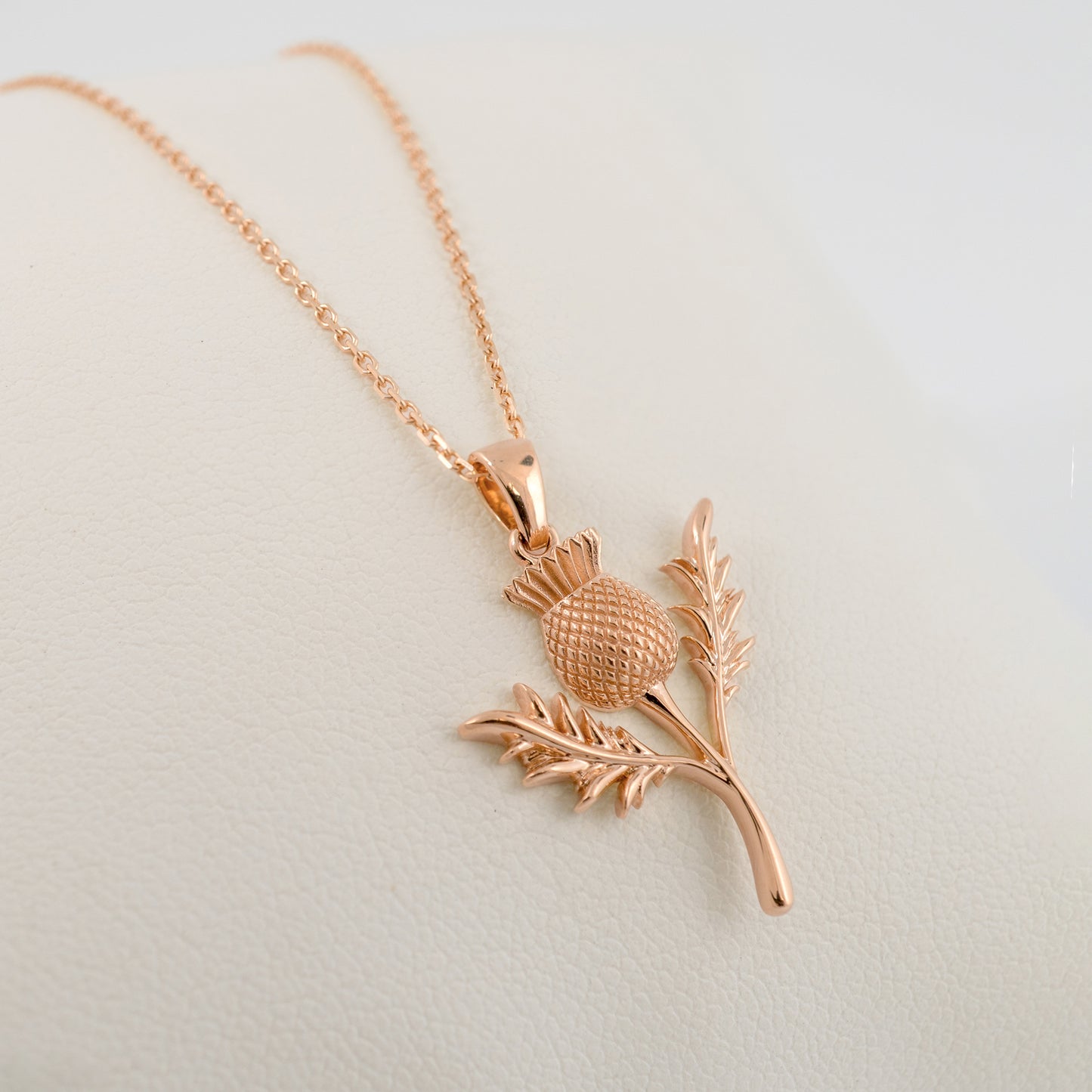 Rose gold thistle pendant necklace on a light background