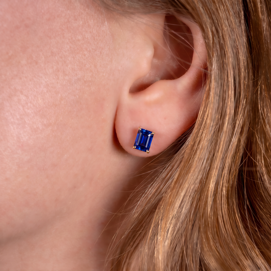 Royal blue rectangle sapphire stud earring worn on the ear