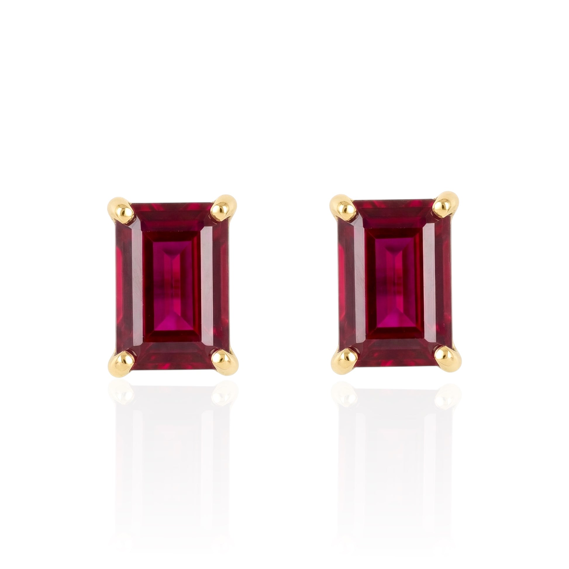 Pair of emerald-cut lab ruby earrings with gold settings on a white background