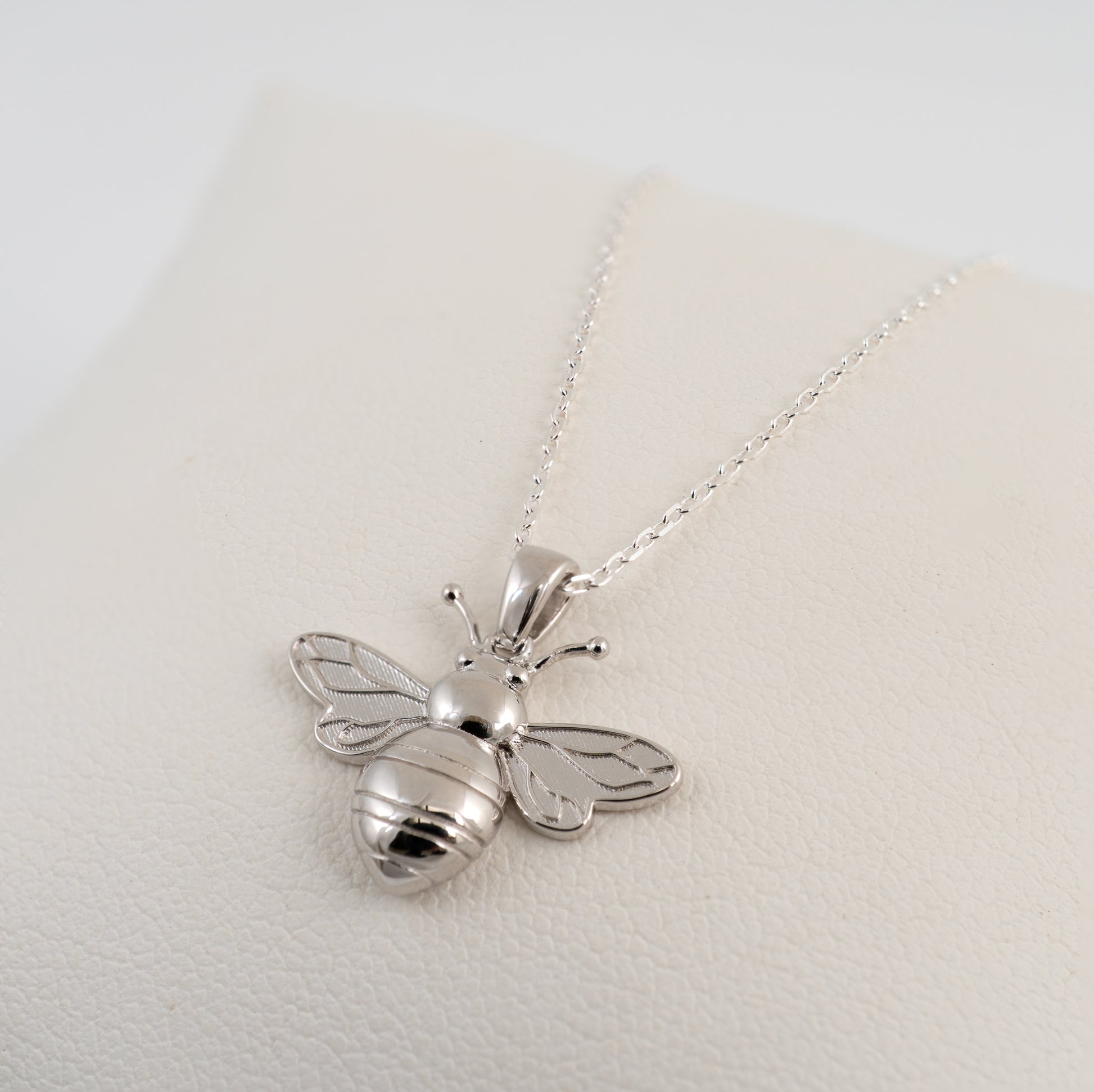 Silver bee pendant necklace on a light gray background