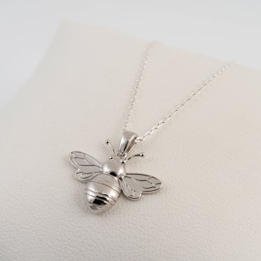 Silver bee pendant necklace on a light gray background