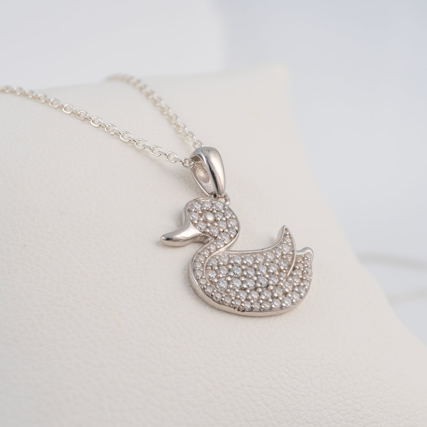 Silver duck-shaped pendant necklace on a light gray background