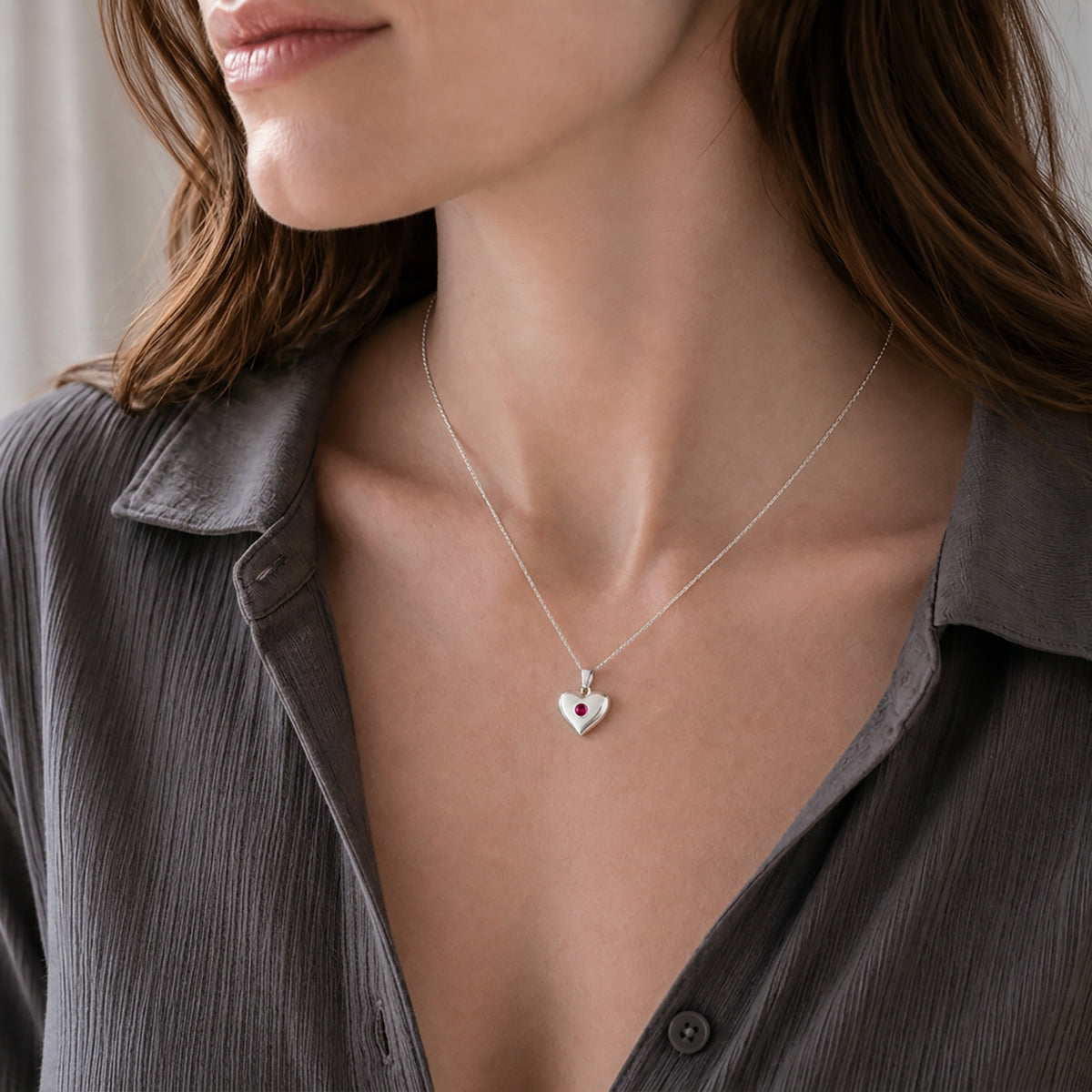 Silver heart necklace with round lab-grown ruby worn on an adjustable sterling silver chain