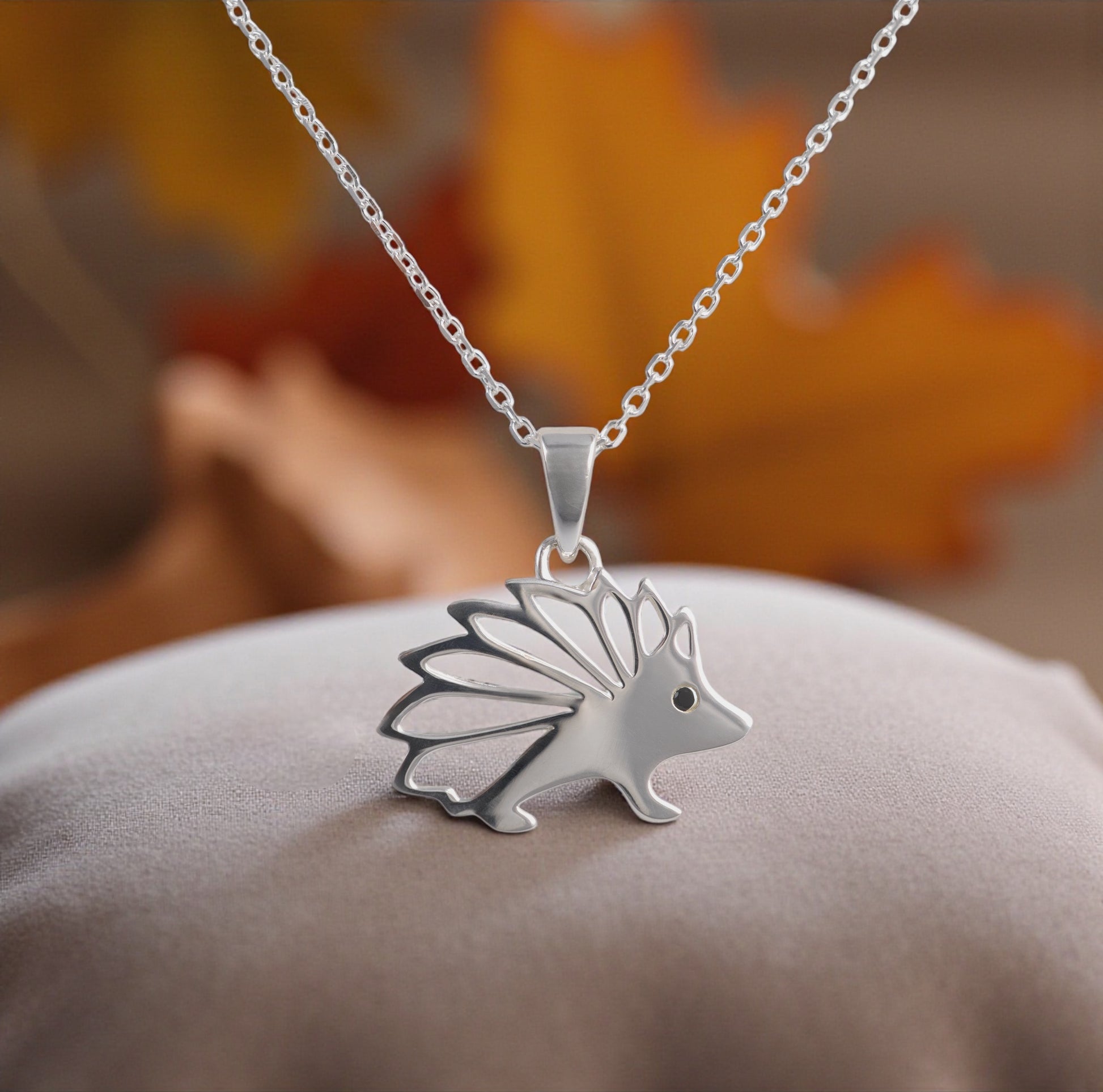 silver hedgehog necklace pendant with leaves in the background