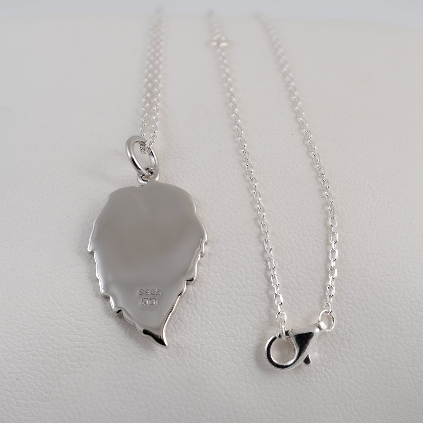 Silver necklace with a leaf-shaped pendant on a light gray background