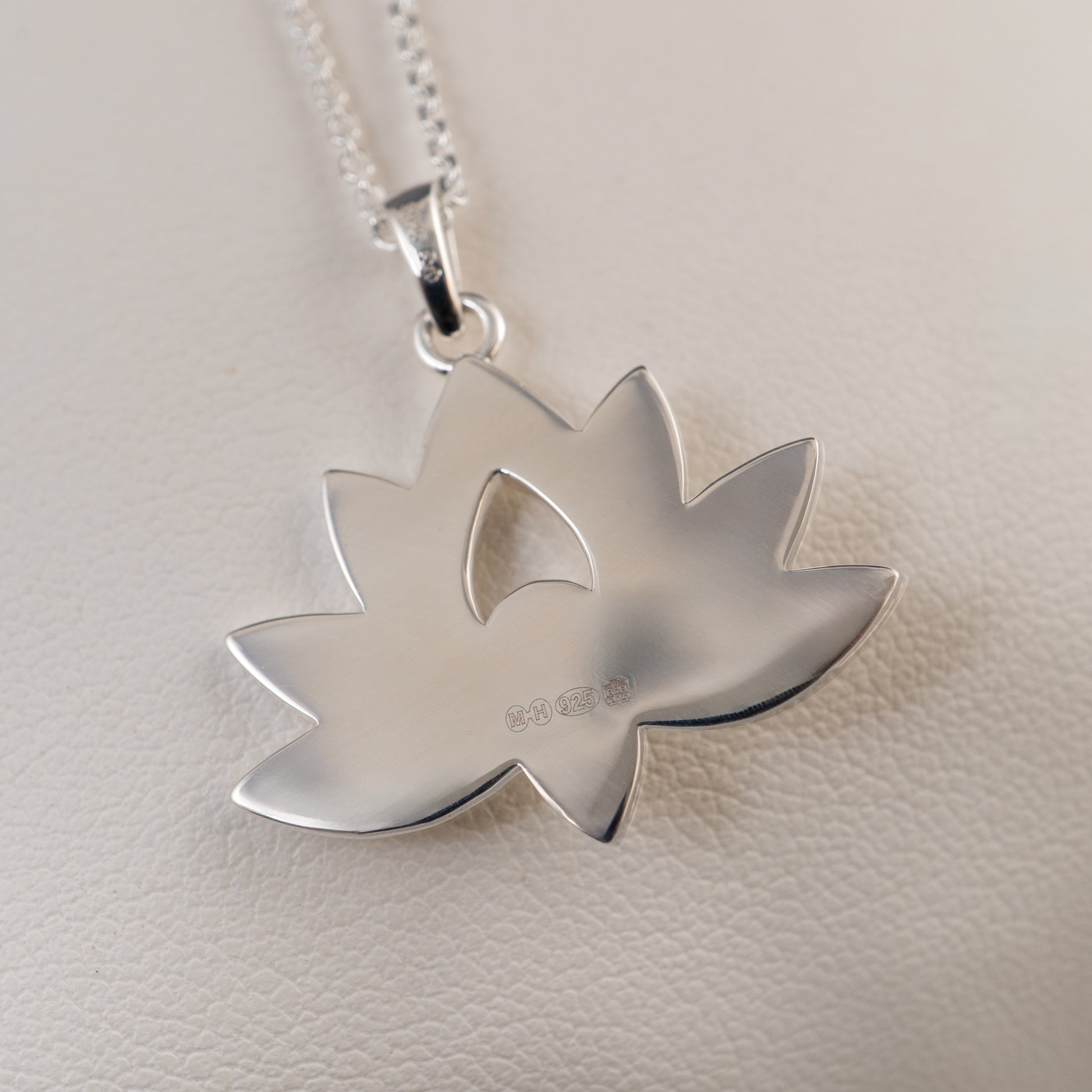 Back view of sterling silver lotus flower pendant showing smooth hallmark surface