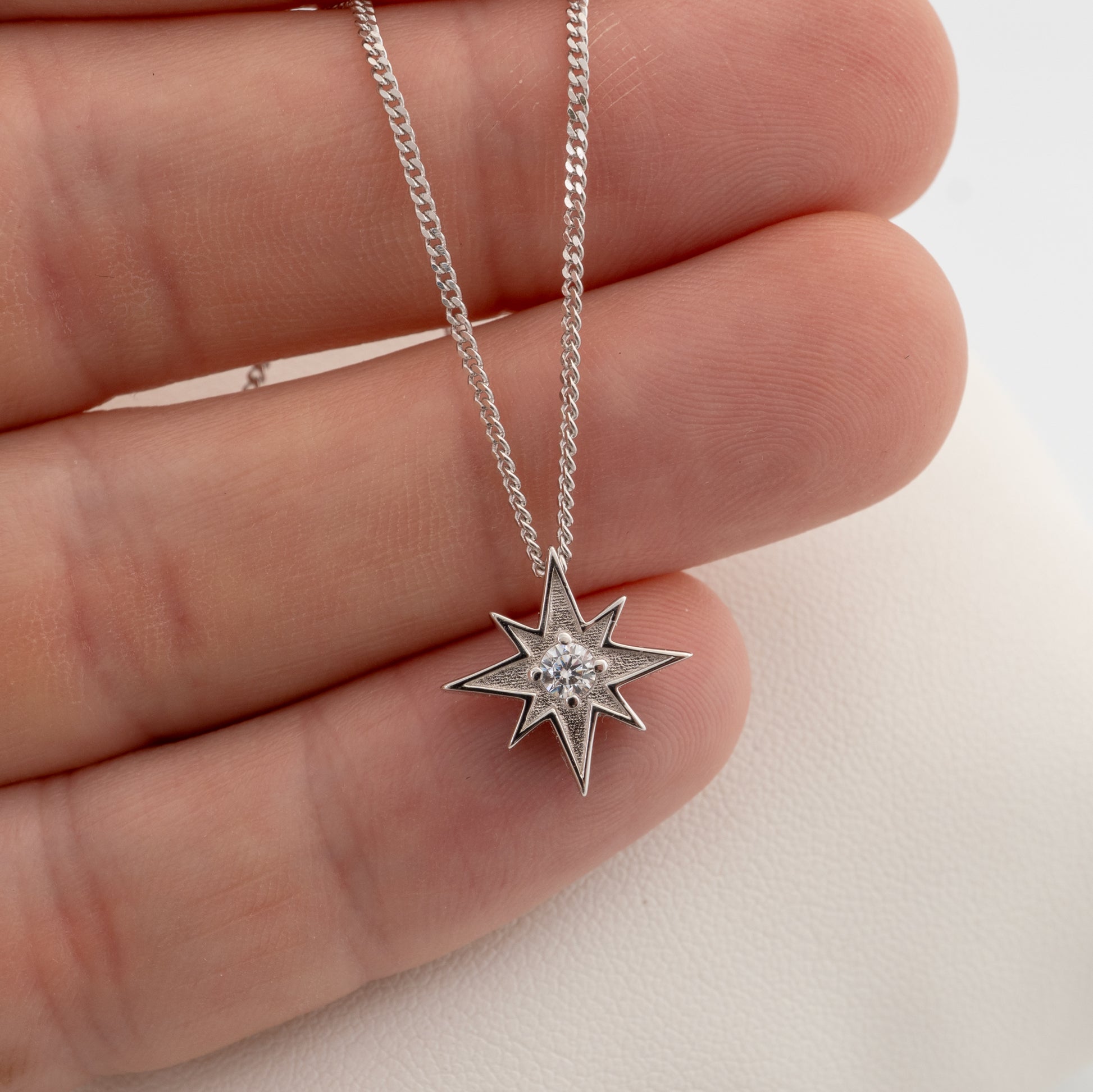 Silver North Star necklace held in hand showing pendant size