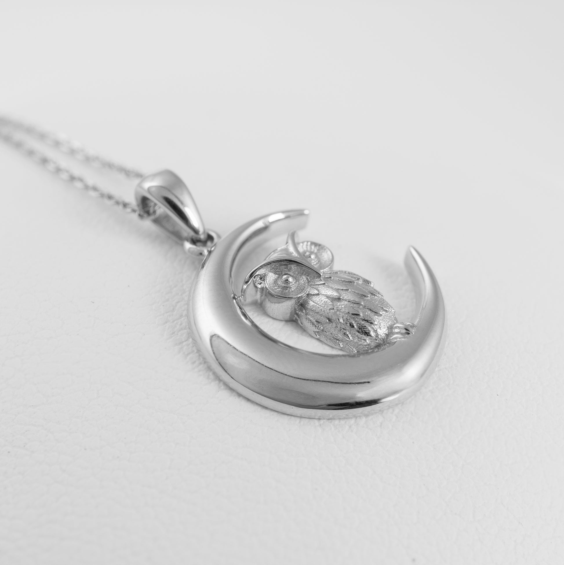 Silver pendant with owl design on a white background