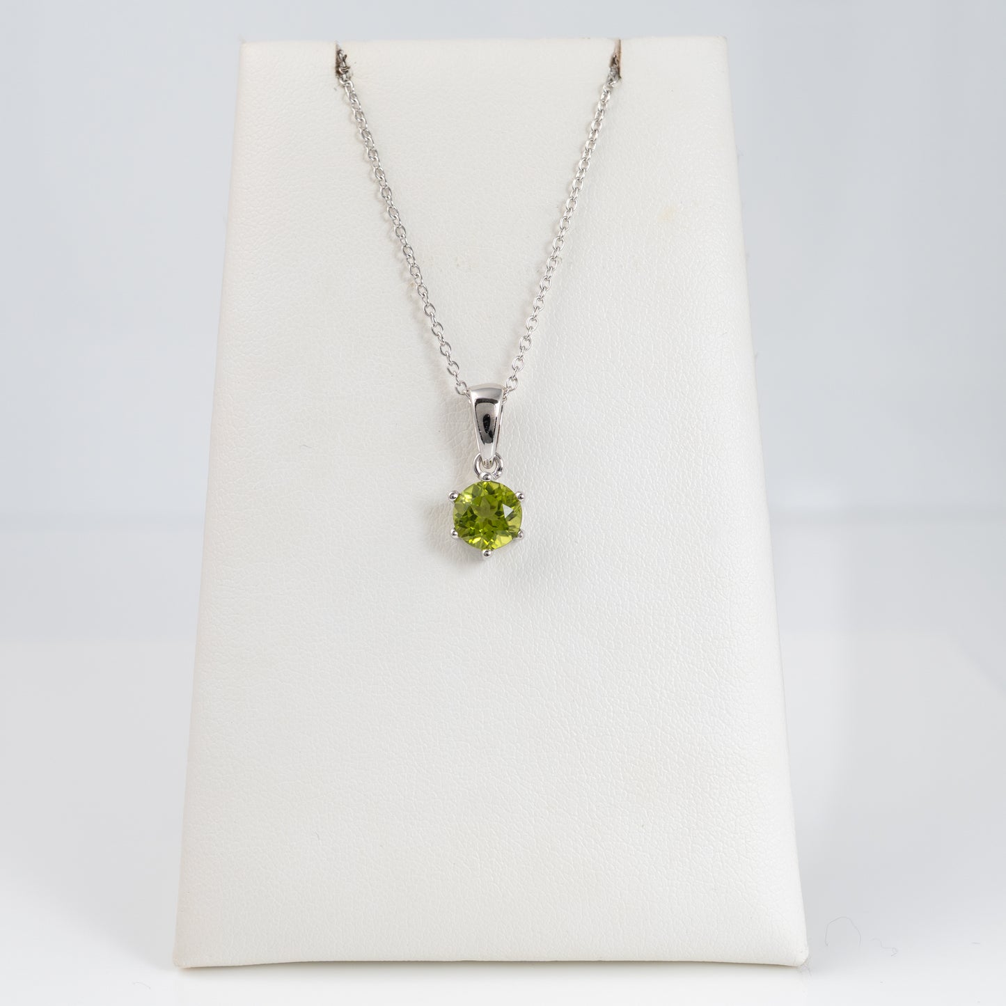 natural peridot pendant on a silver chain displayed on a white card