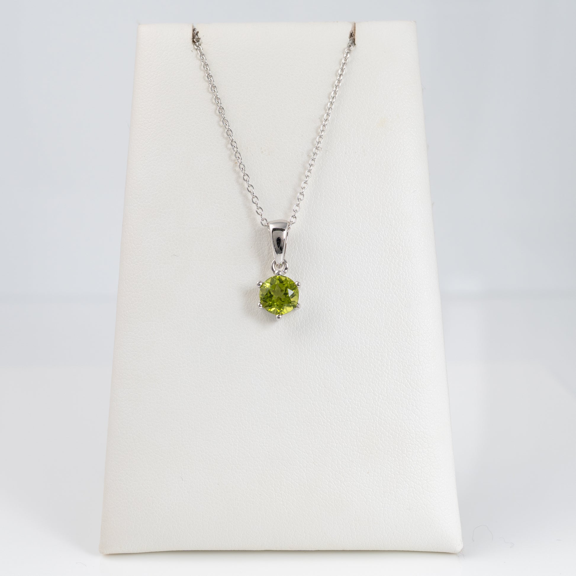 natural peridot pendant on a silver chain displayed on a white card