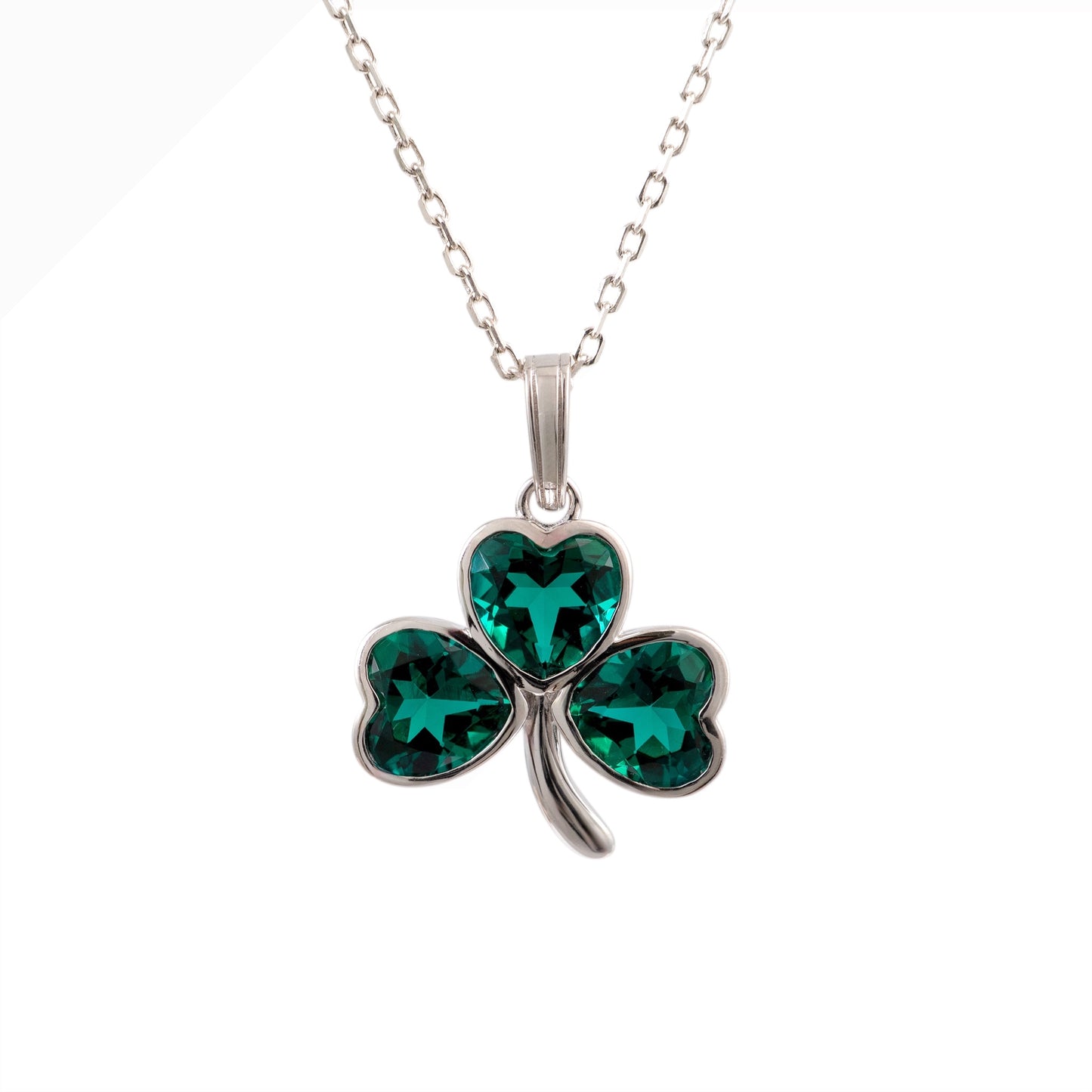 A sterling silver shamrock pendant necklace with three heart-shaped emerald green crystals, shown on a white background.