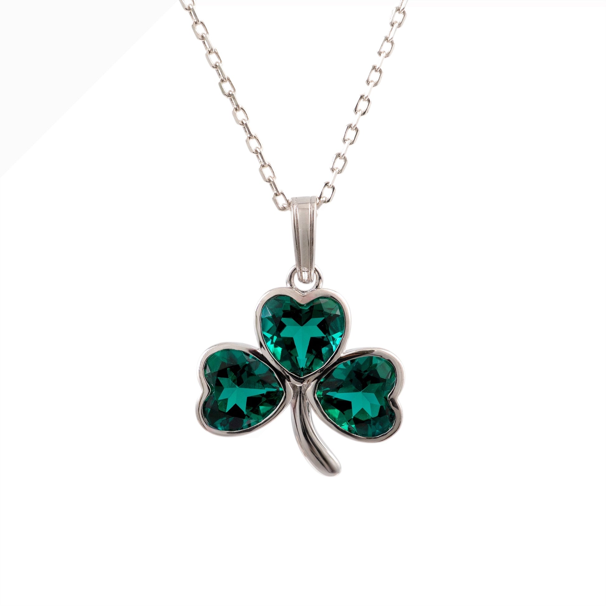 A sterling silver shamrock pendant necklace with three heart-shaped emerald green crystals, shown on a white background.