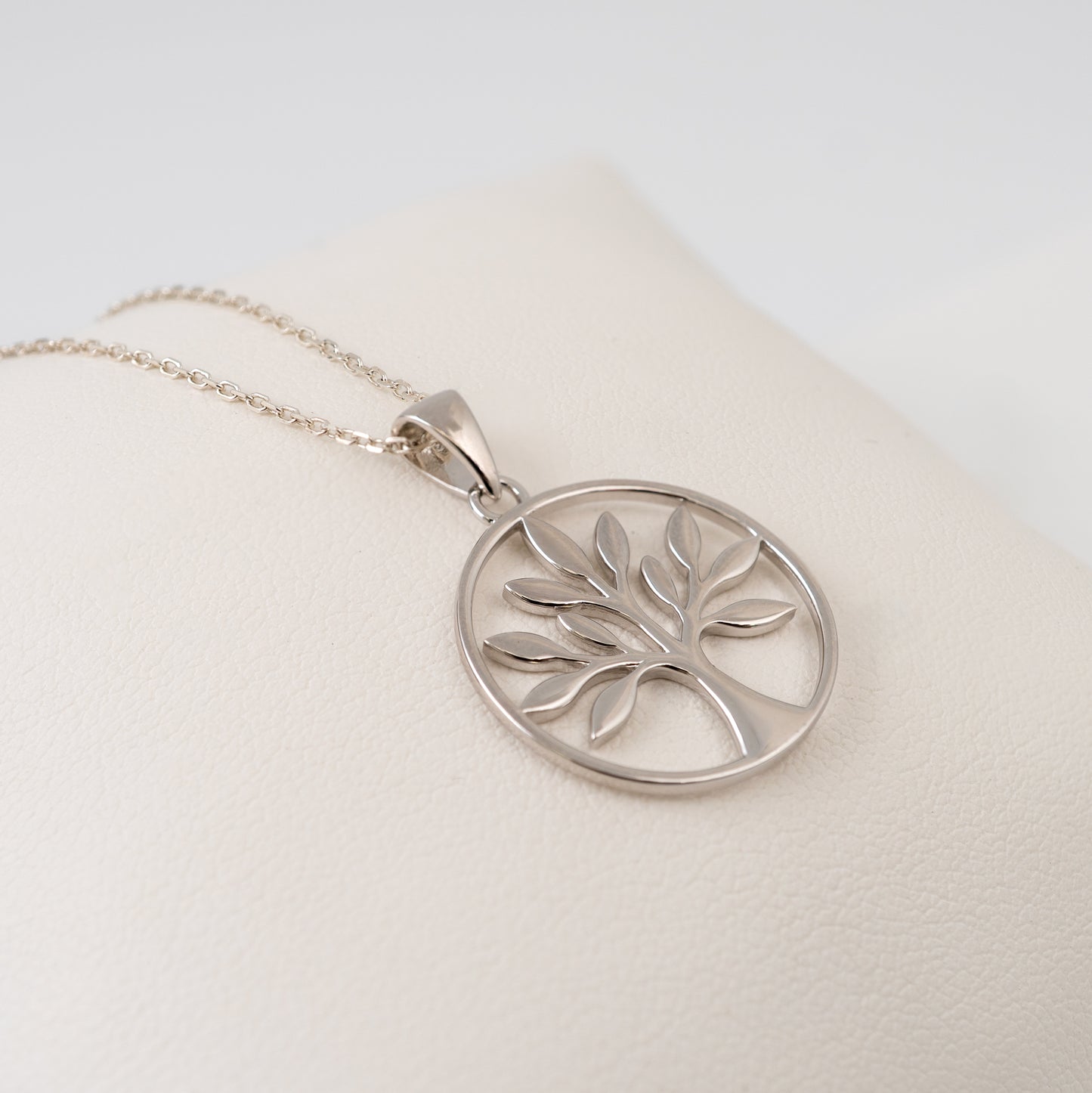 silver tree of life necklace side view on white cushion
