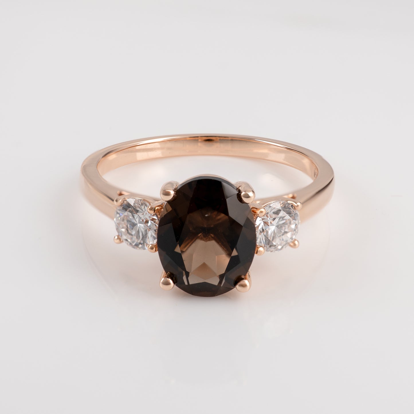 smoky quartz ring with a central black gemstone and two smaller clear gemstones on a light gray background