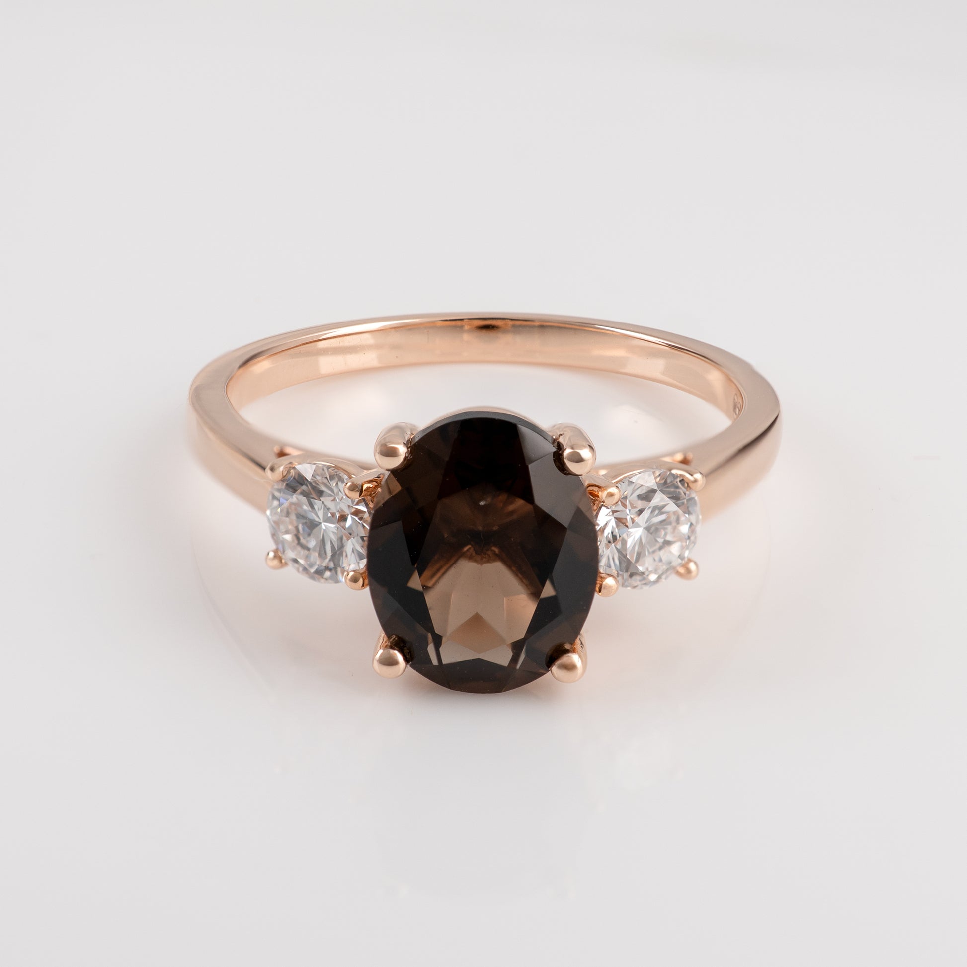 smoky quartz ring with a central black gemstone and two smaller clear gemstones on a light gray background