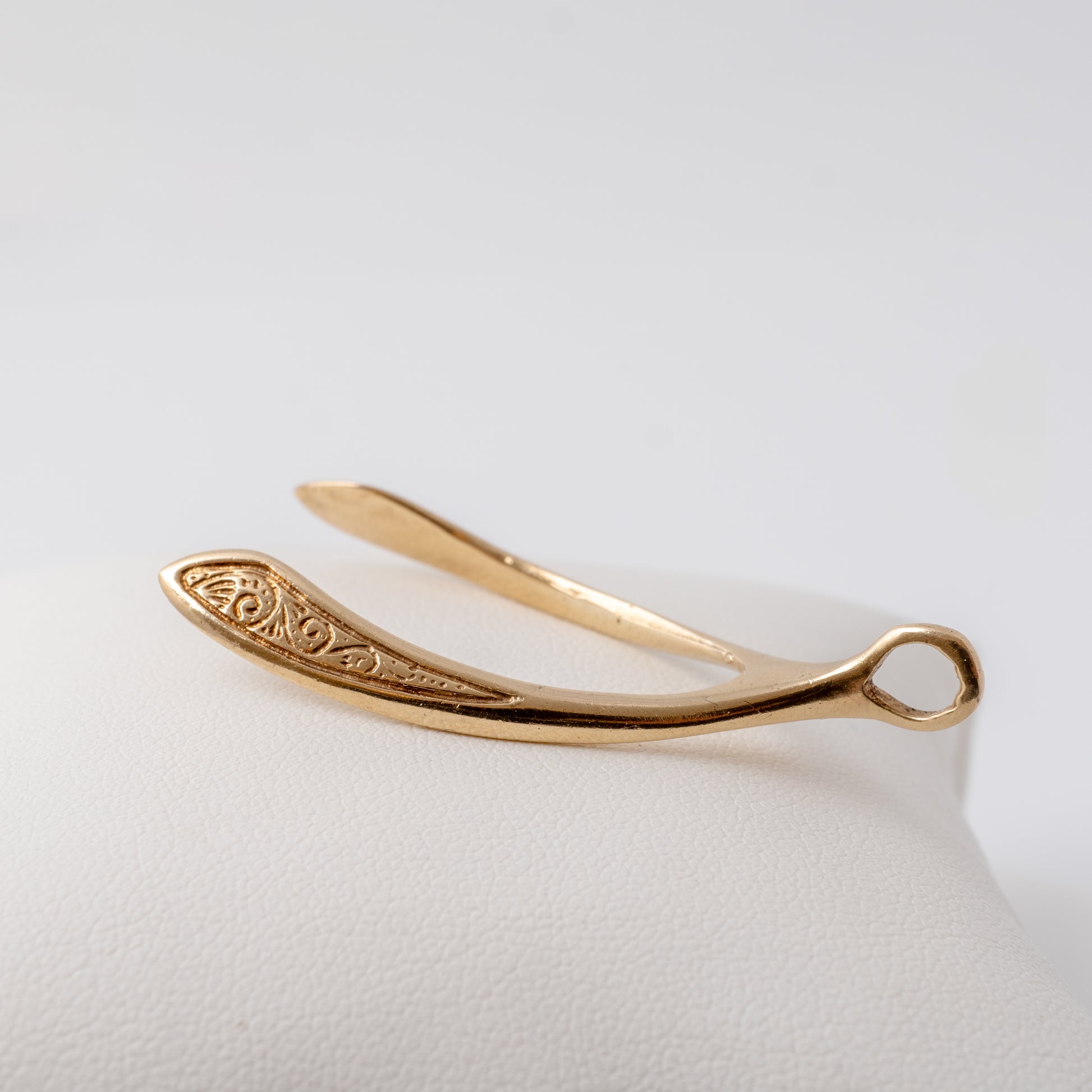 Side view of a solid gold wishbone pendant showing intricate scroll detailing, crafted in vintage 9ct yellow gold