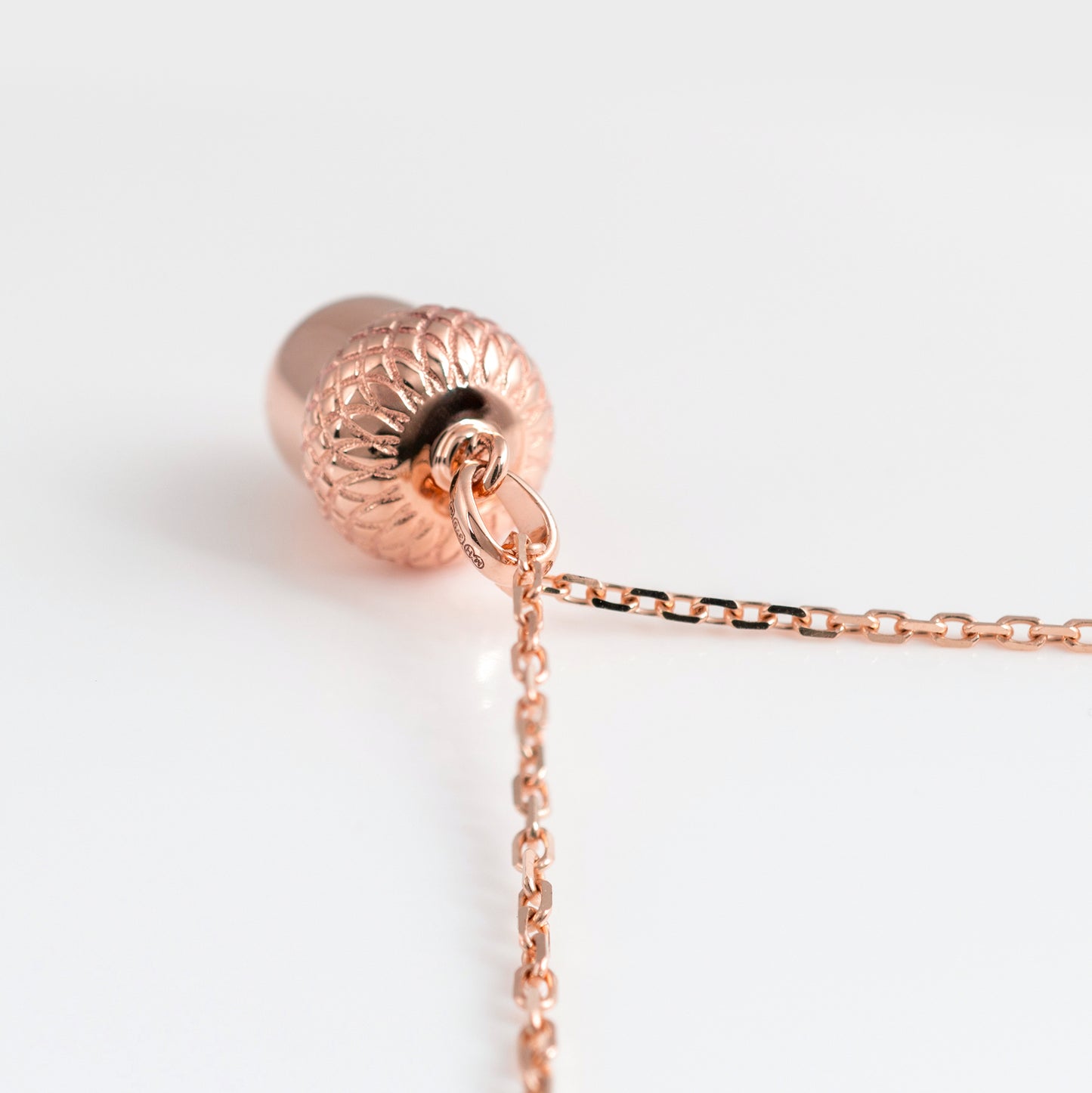 Rose gold necklace with a detailed pendant on a white background
