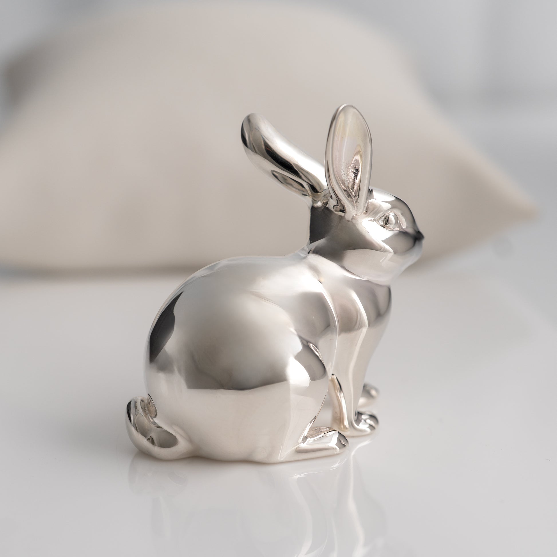 Silver rabbit figurine on a light gray background