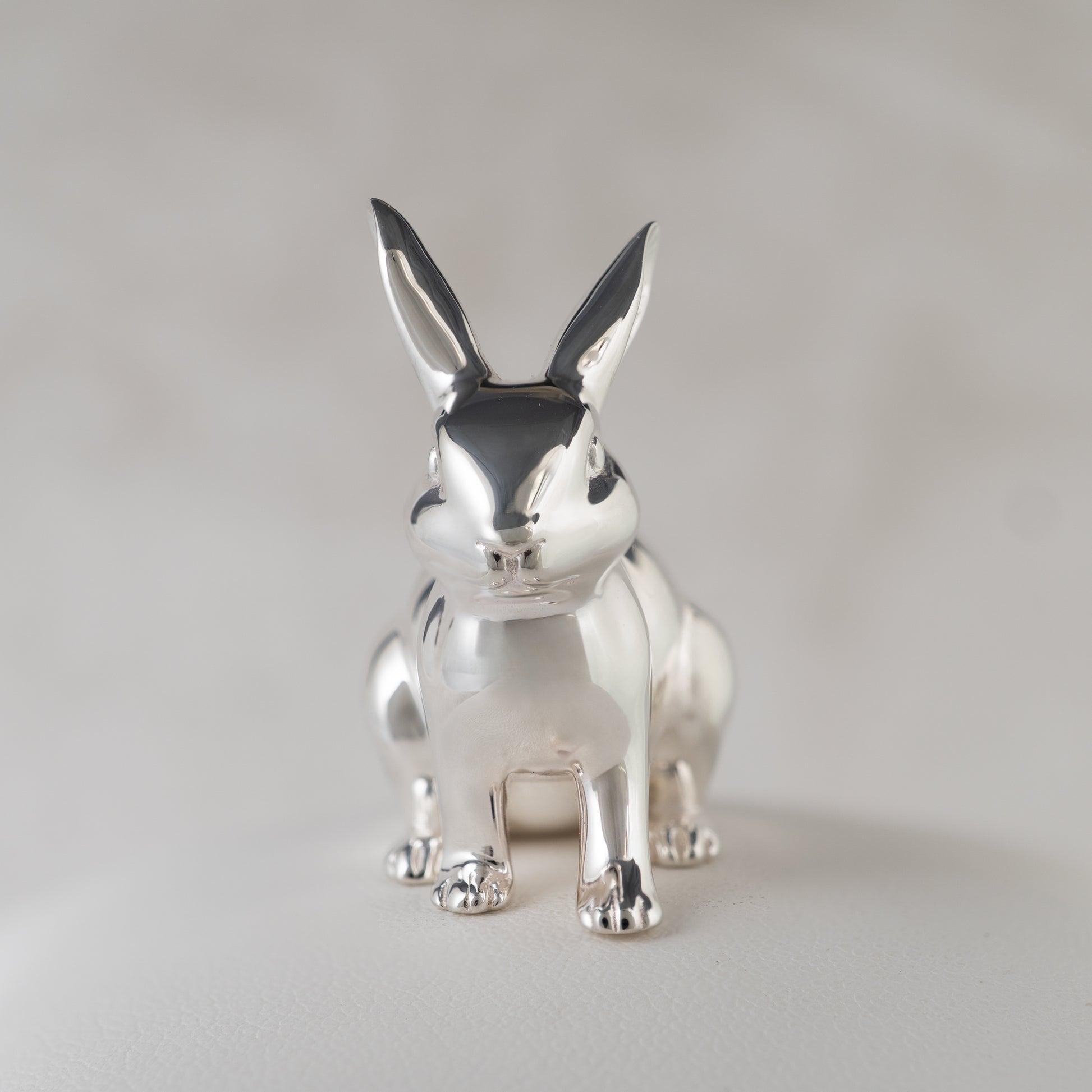 Silver rabbit figurine front view on a light gray background