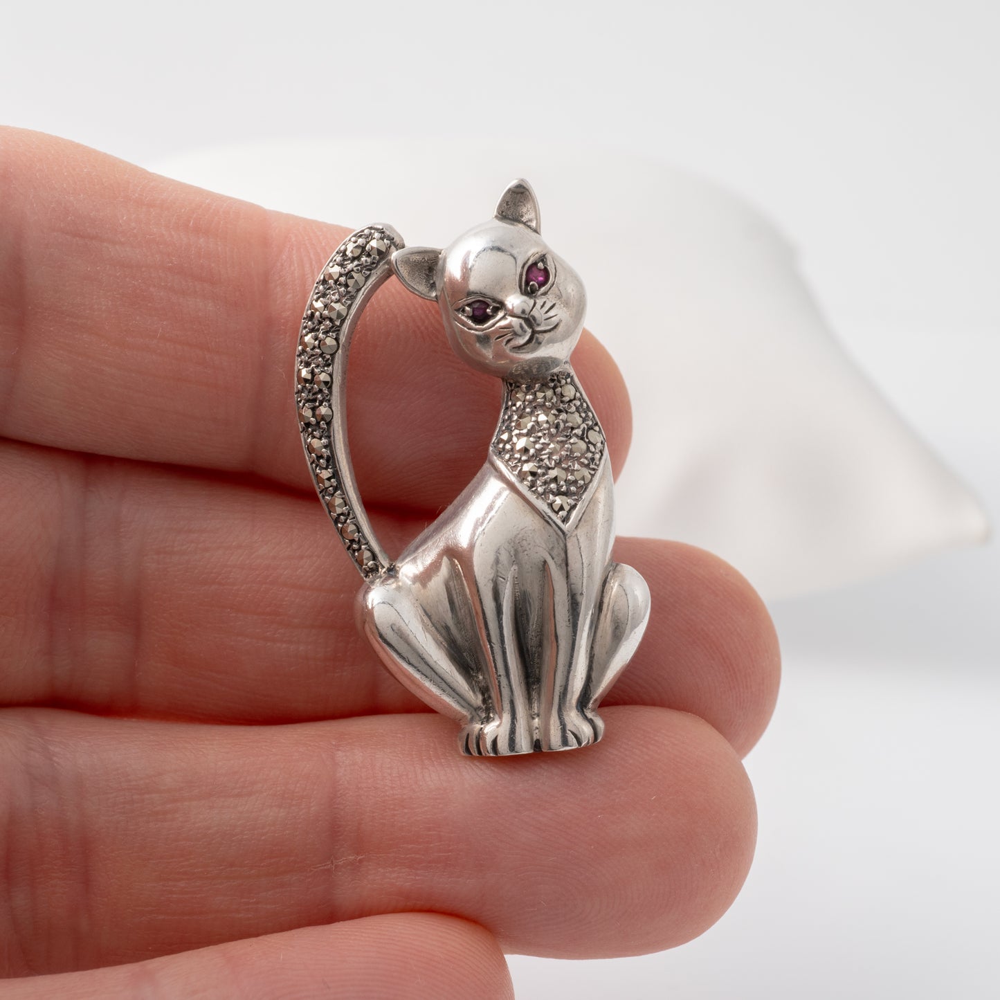 holding vintage sterling silver cat brooch showcasing ruby eyes and marcasite decoration – ideal for cat lovers