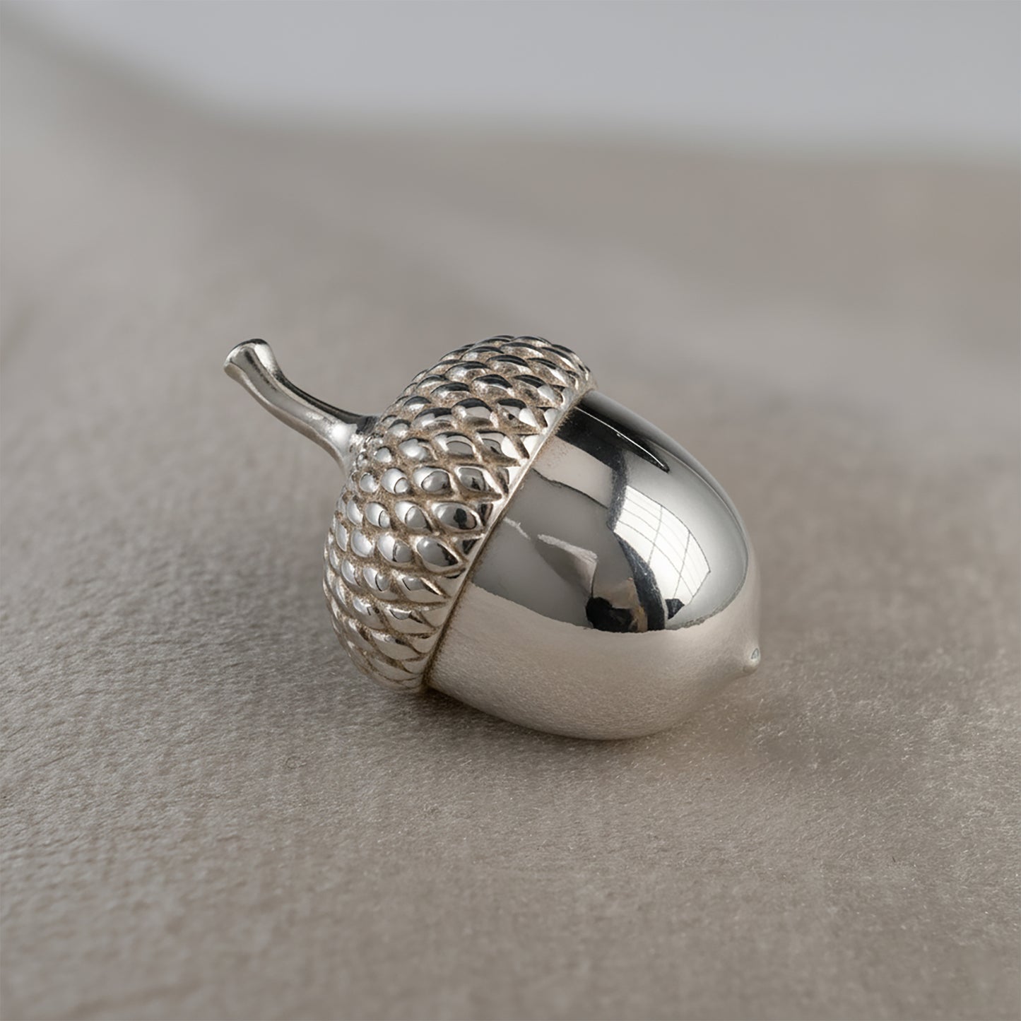 Silver acorn-ornament  on a neutral background