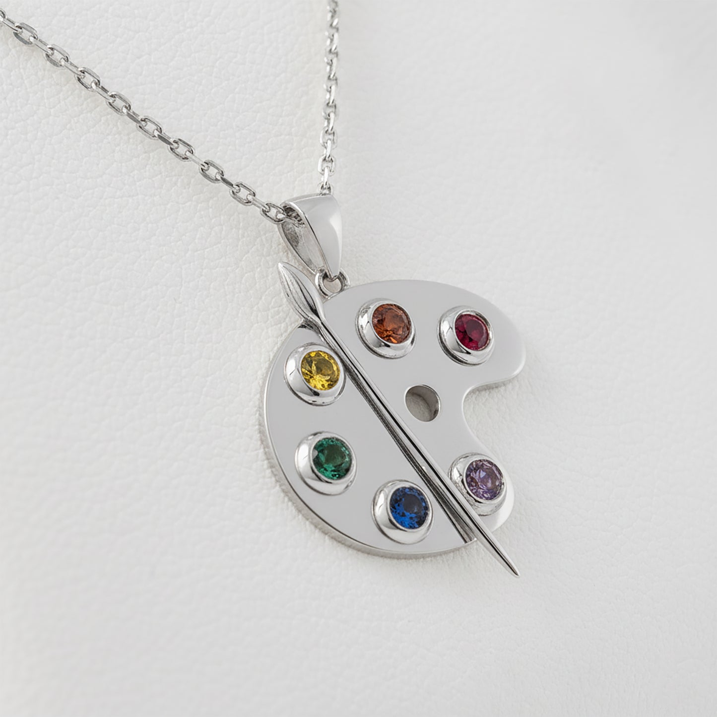 Silver artist paint palette pendant featuring colorful gemstones on a light gray background