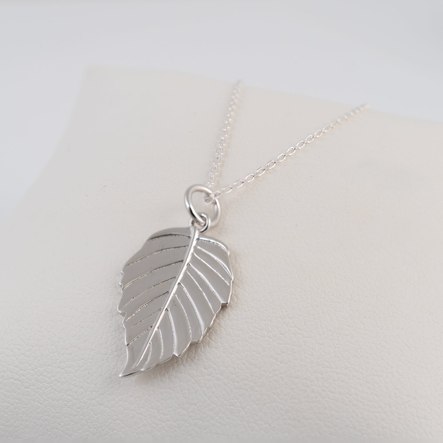 Silver leaf pendant necklace on a light gray background