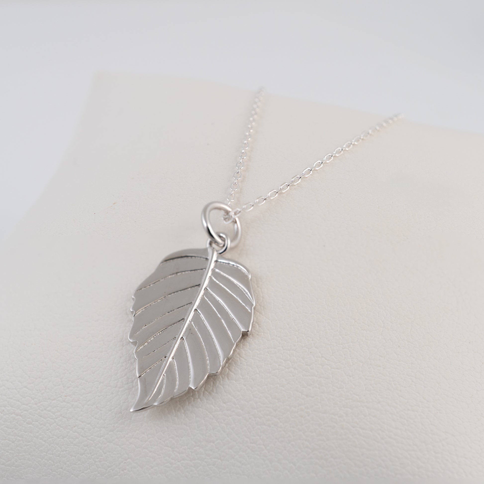 Silver leaf pendant necklace on a light gray background