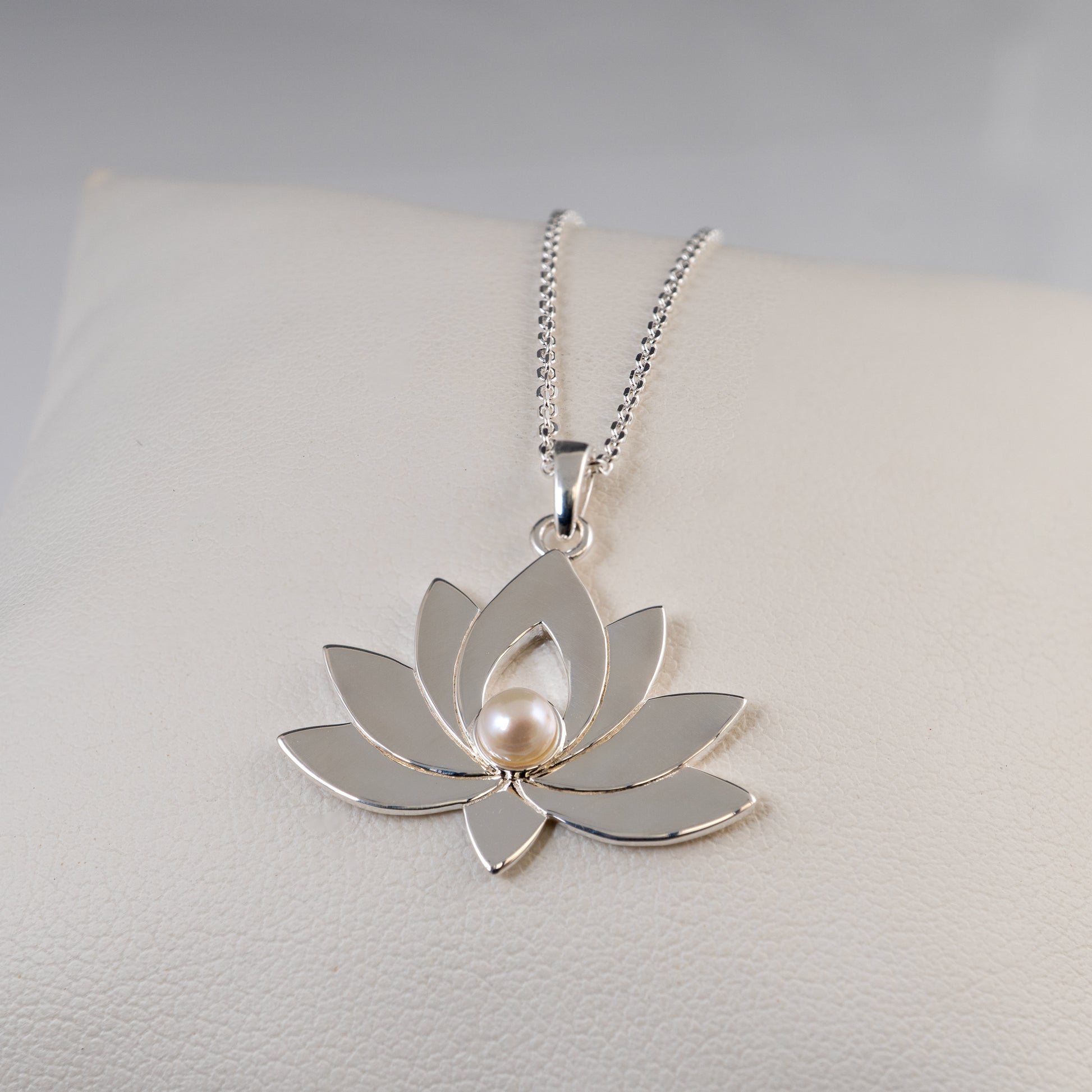 Silver lotus flower pendant necklace on a light gray background