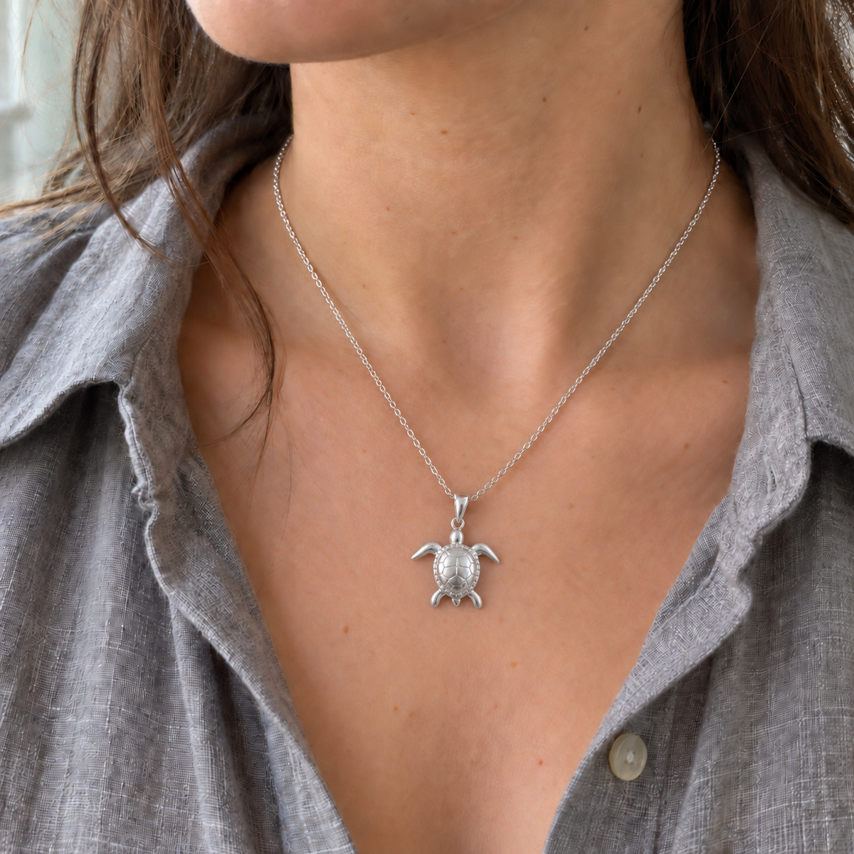 AI visualisation of a silver sea turtle necklace worn by a model with a grey open-neck shirt