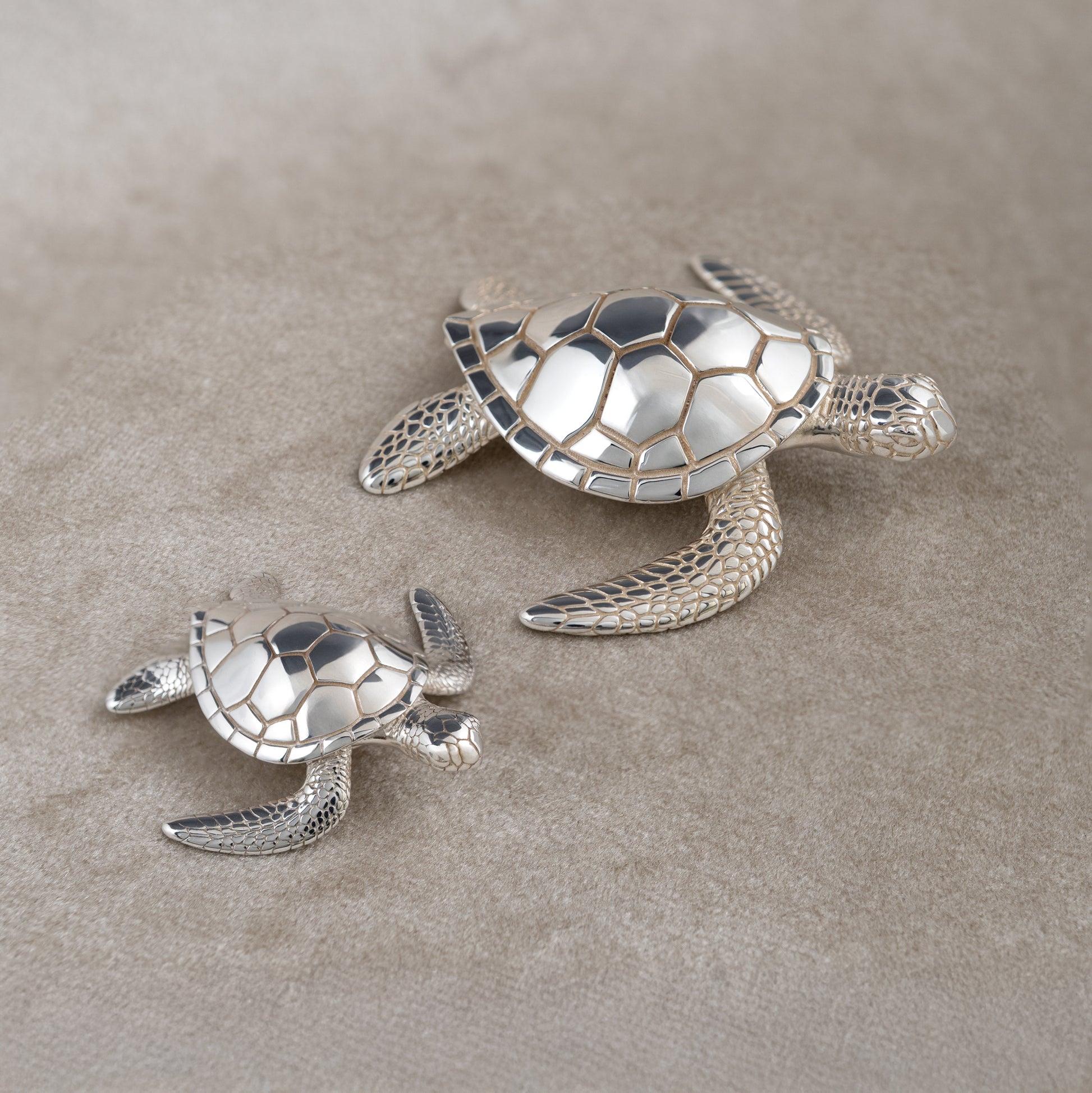 Sterling silver sea turtle figurines small and large on soft beige background