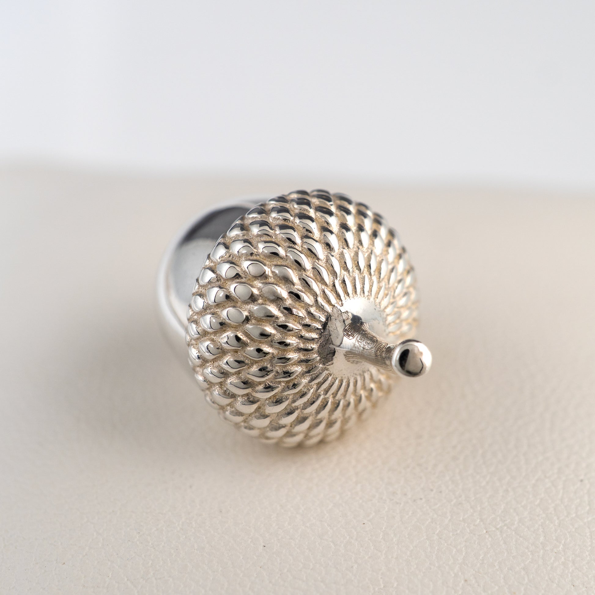 Hallmarked sterling silver acorn ornament showing textured detailing and hallmarked stem