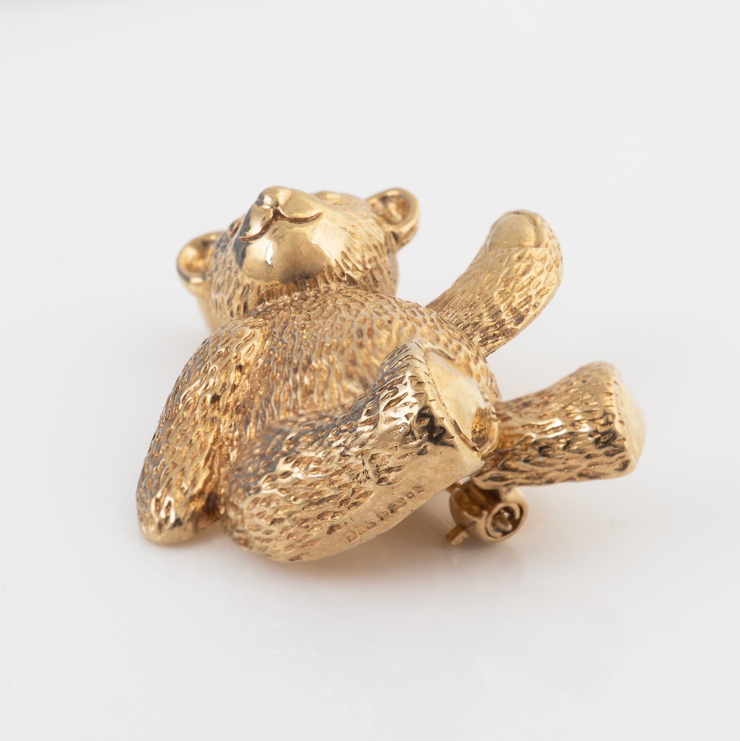 Reverse view of a 9ct gold teddy bear brooch showing the London hallmarks, gold pin and rollover safety catch.