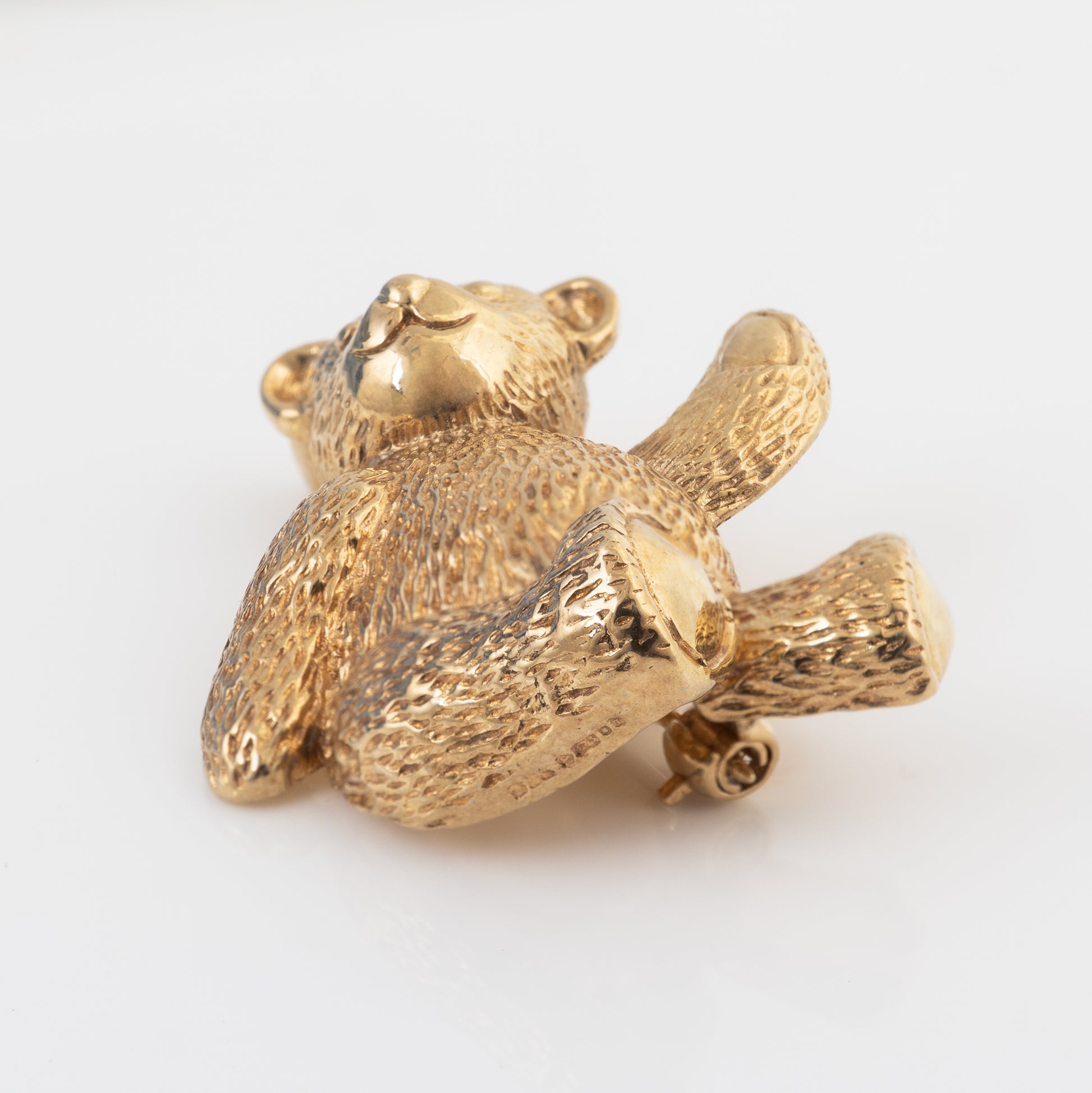Reverse view of a 9ct gold teddy bear brooch showing the London hallmarks, gold pin and rollover safety catch.