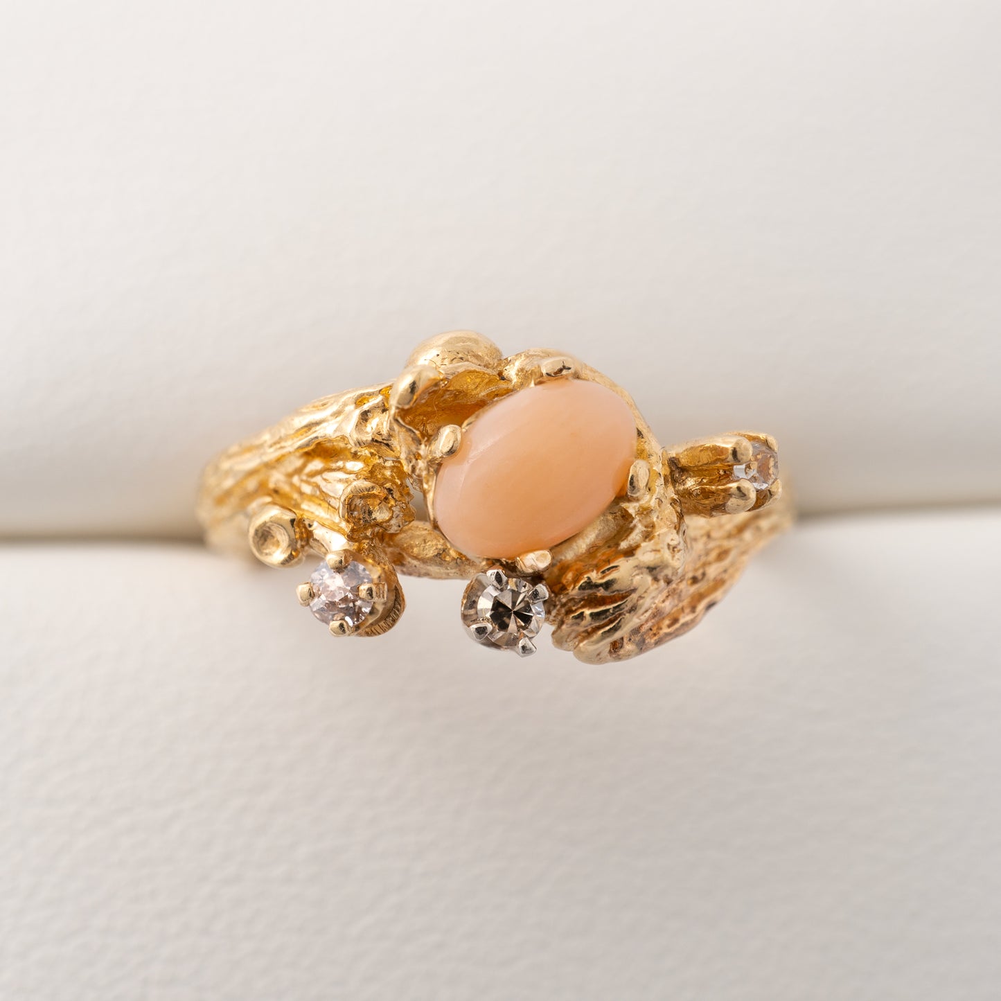 Vintage coral ring with diamonds displayed on a cushion, highlighting the organic gold texture