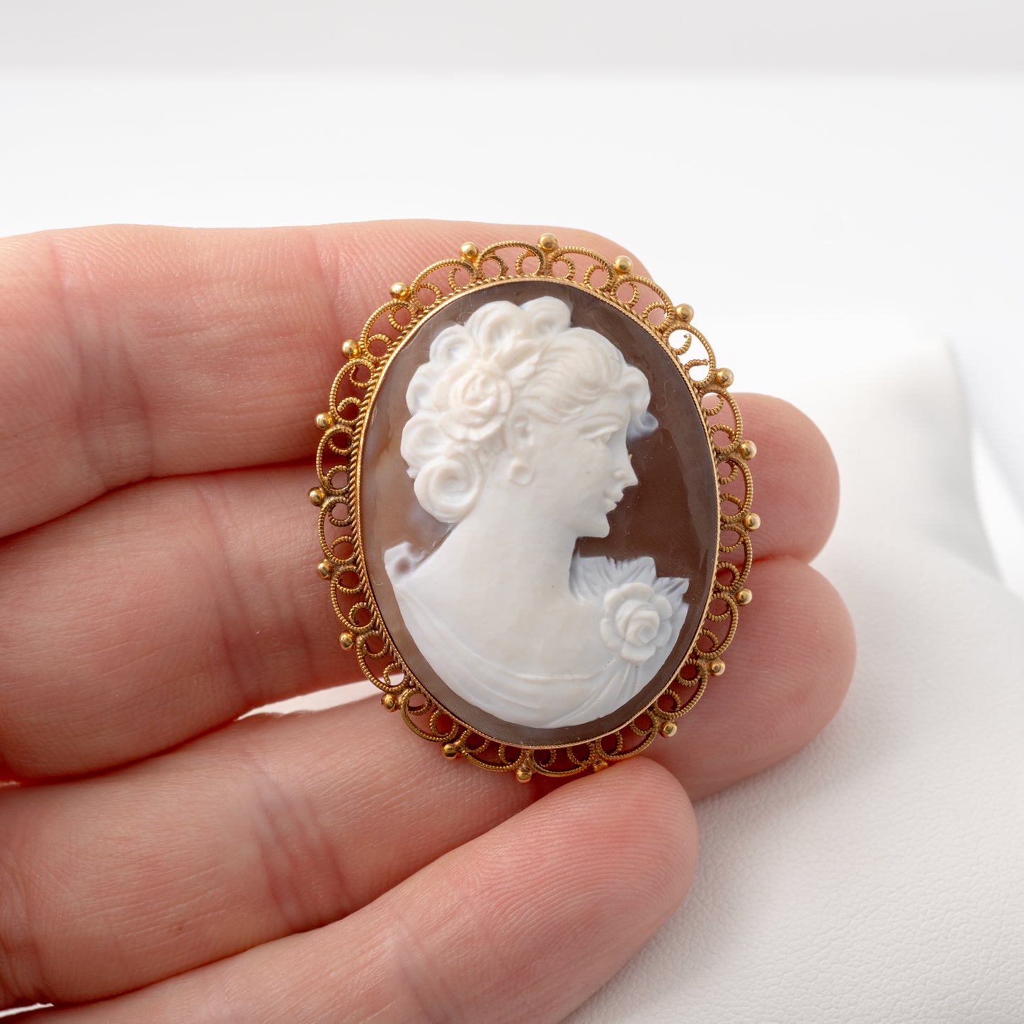 Vintage gold cameo brooch in a hand to display size